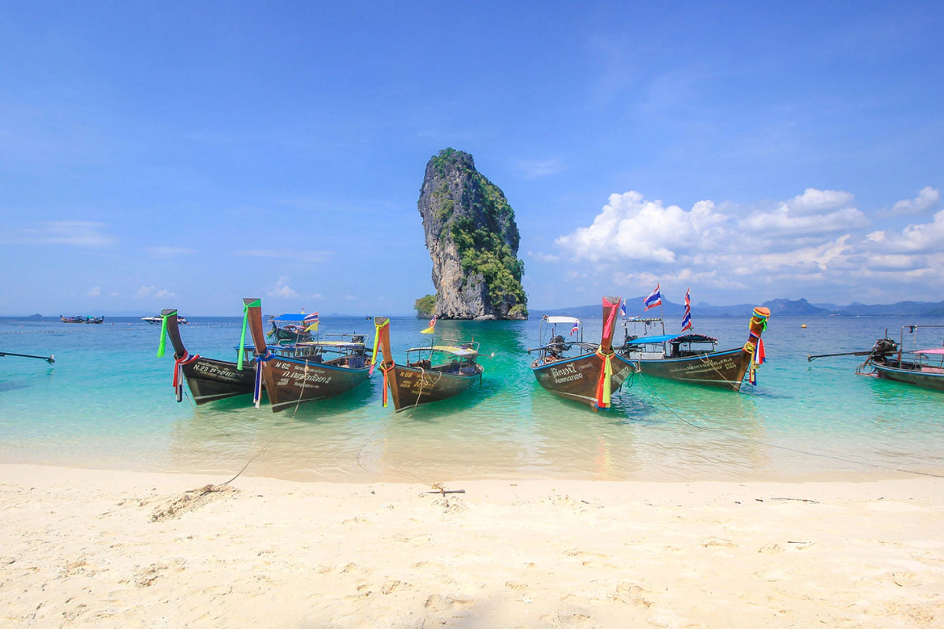Traditional boats on beach in Krabi with rock island