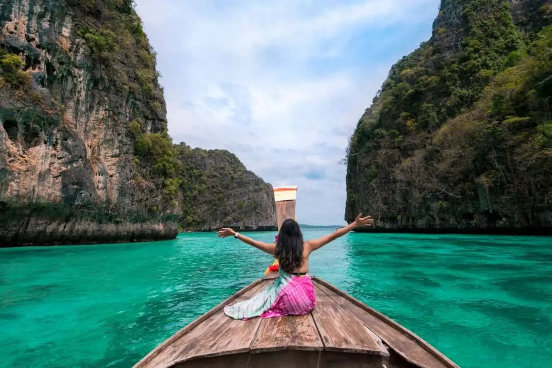 Woman on boat in Phuket with tall cliff walls