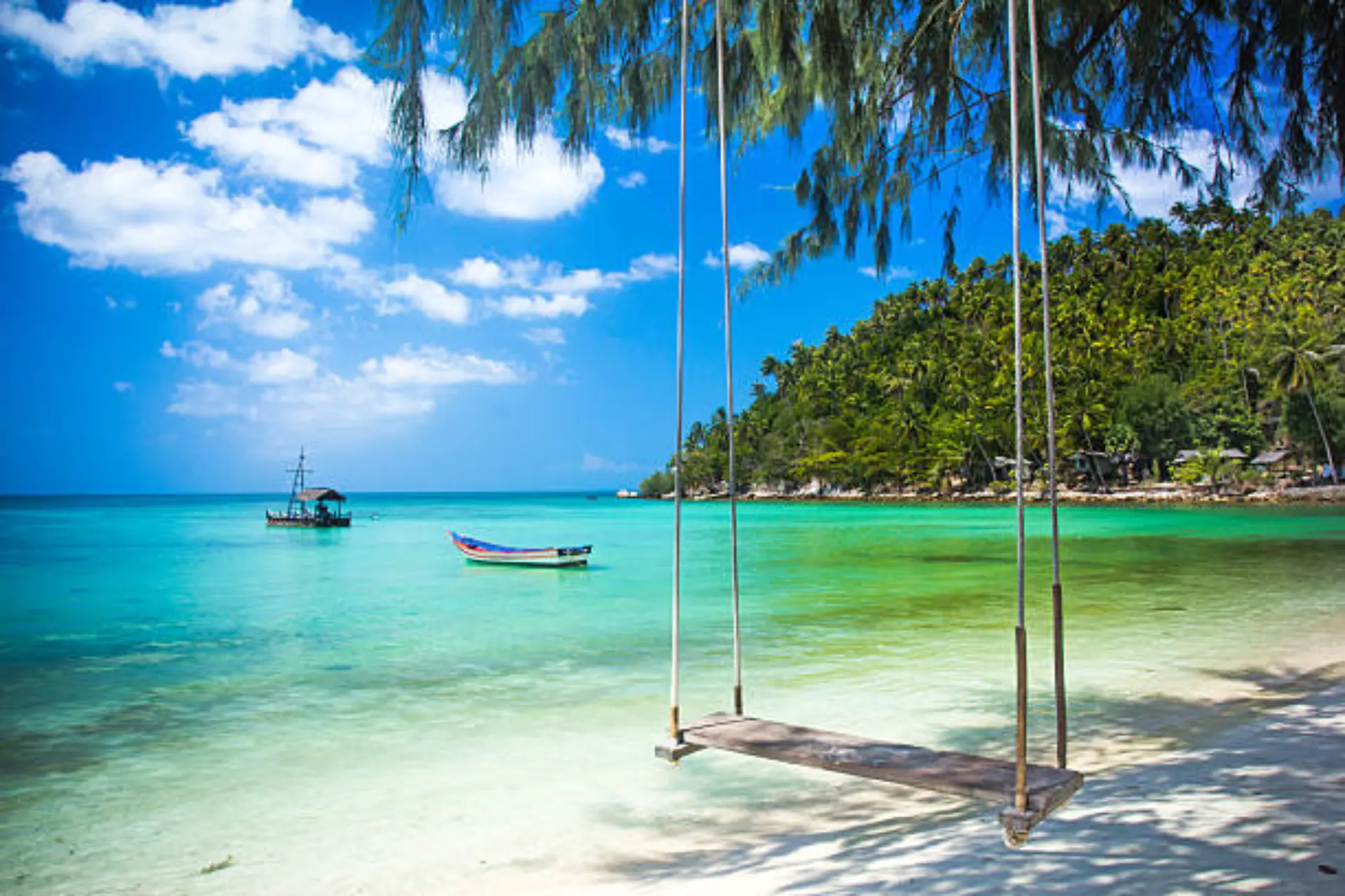 Rope swing hanging over clear water beach Thailand