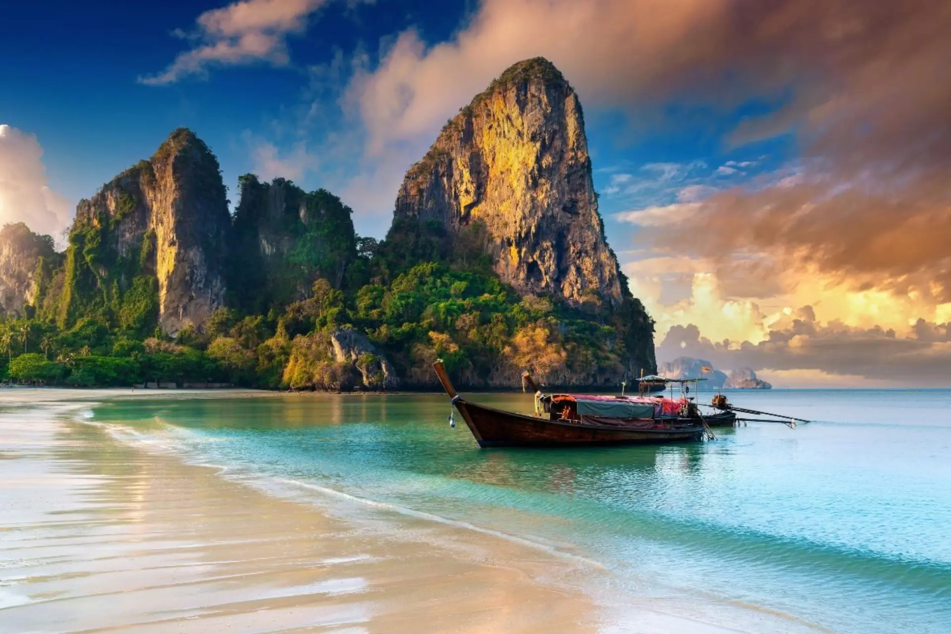Wooden boat floating in shallow water at Krabi beach