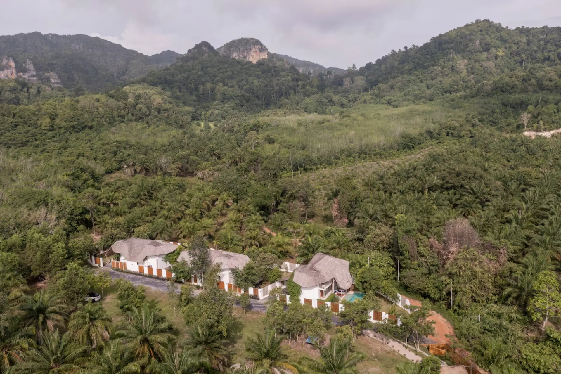 White buildings with brown roofs nestled in Krabi jungle valley