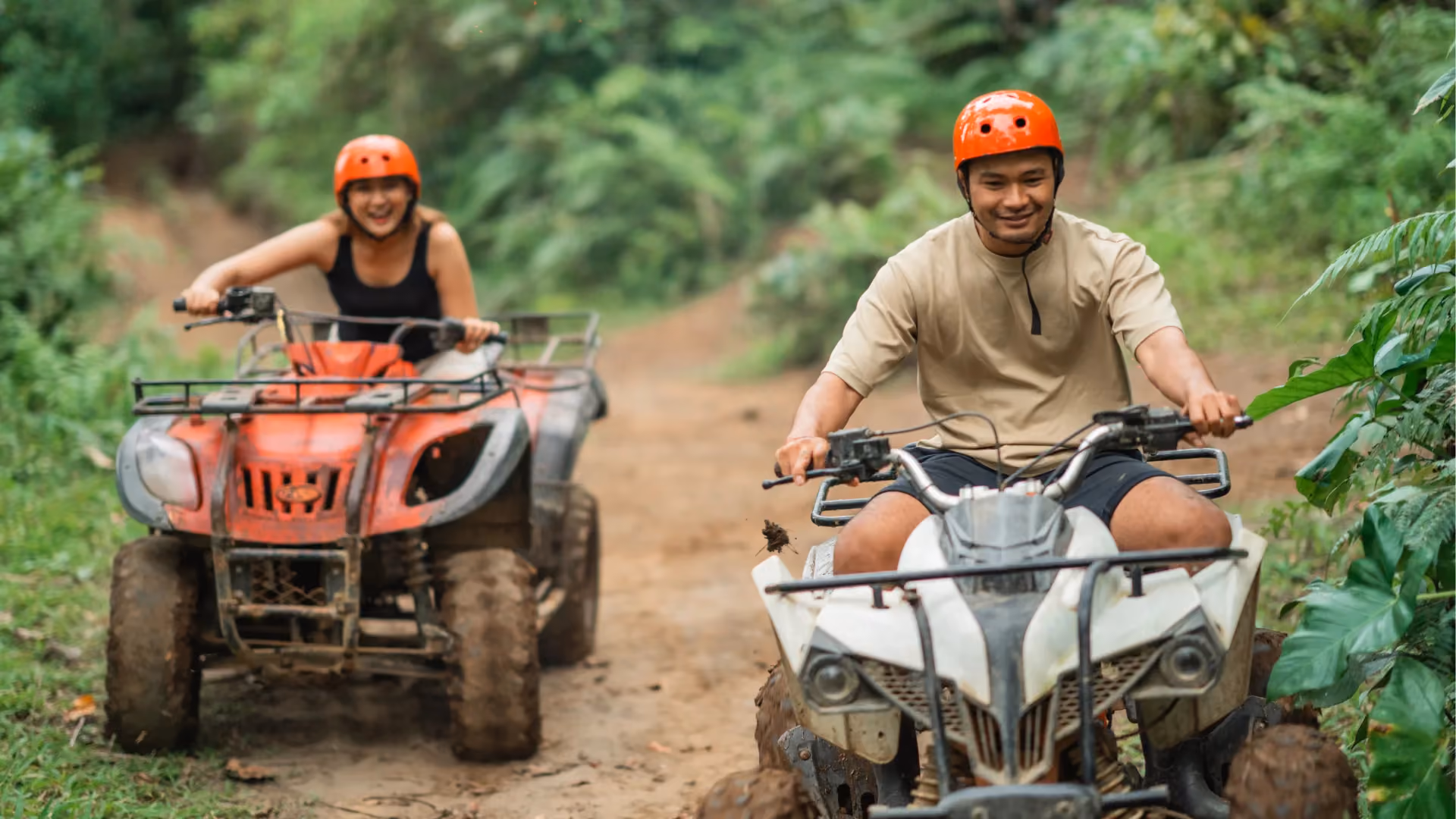 Two people riding ATVs on dirt path in Phuket jungle