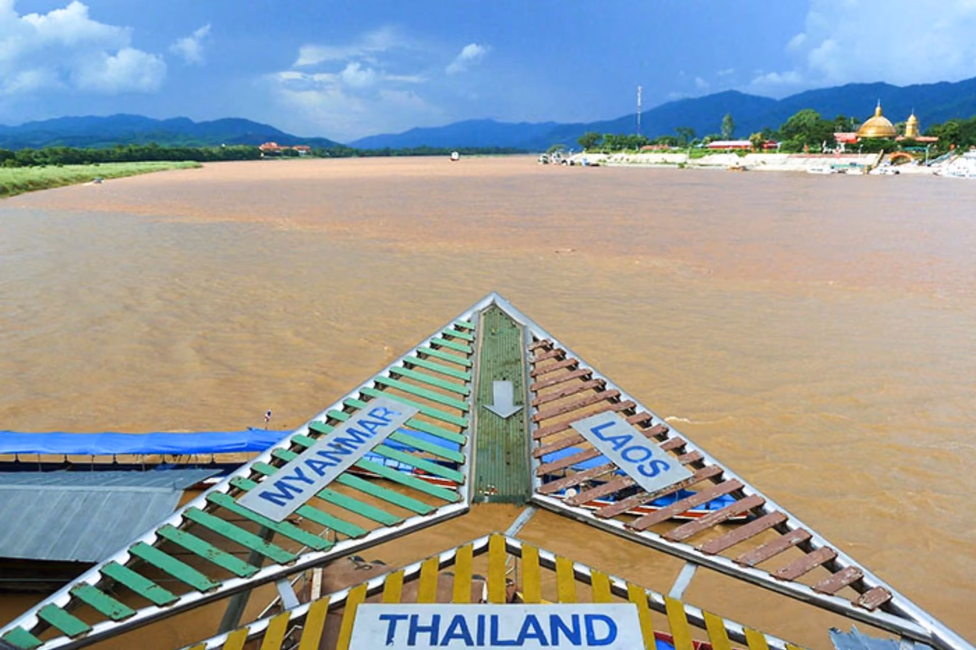 Boat bow with Thailand and Laos signs on river, mountains behind