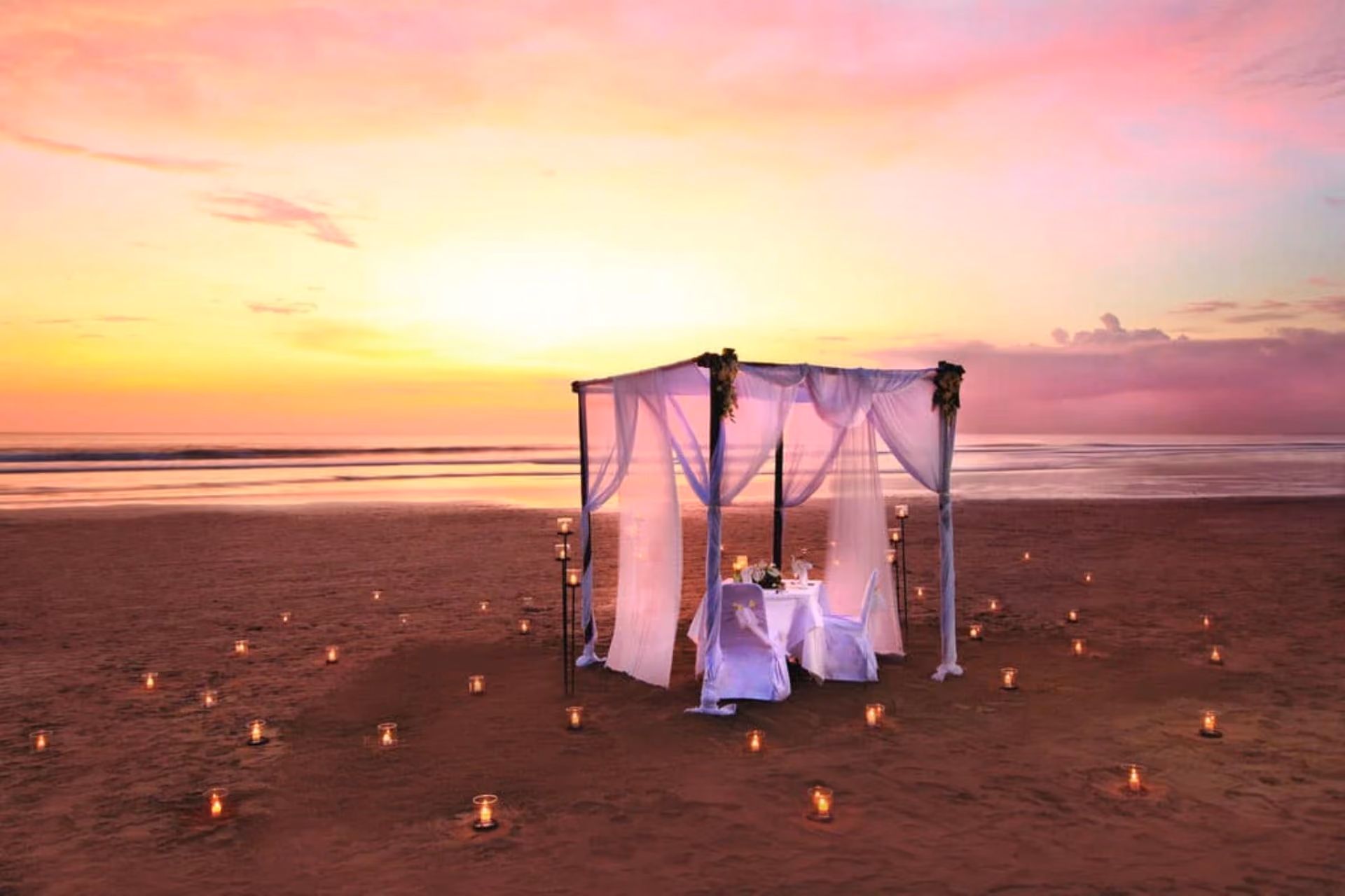 Candlelit dinner table on beach at sunset