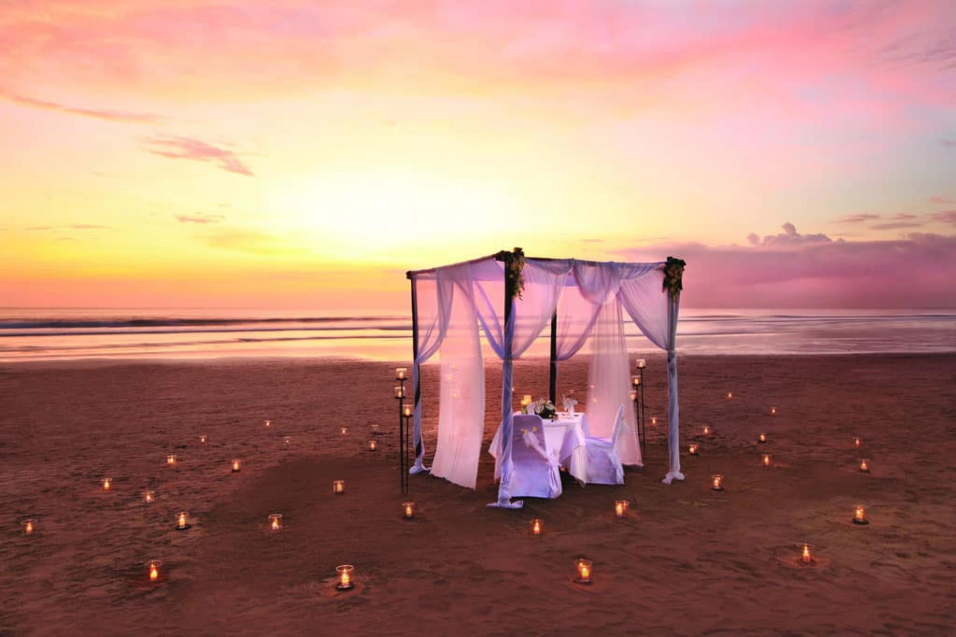 Candlelit dinner table on beach at sunset