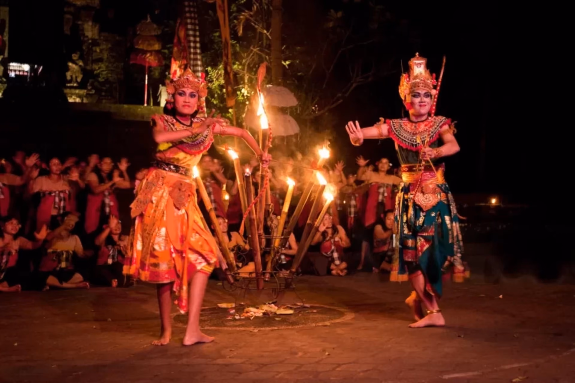 Kecak fire dance performers with lit torches at night