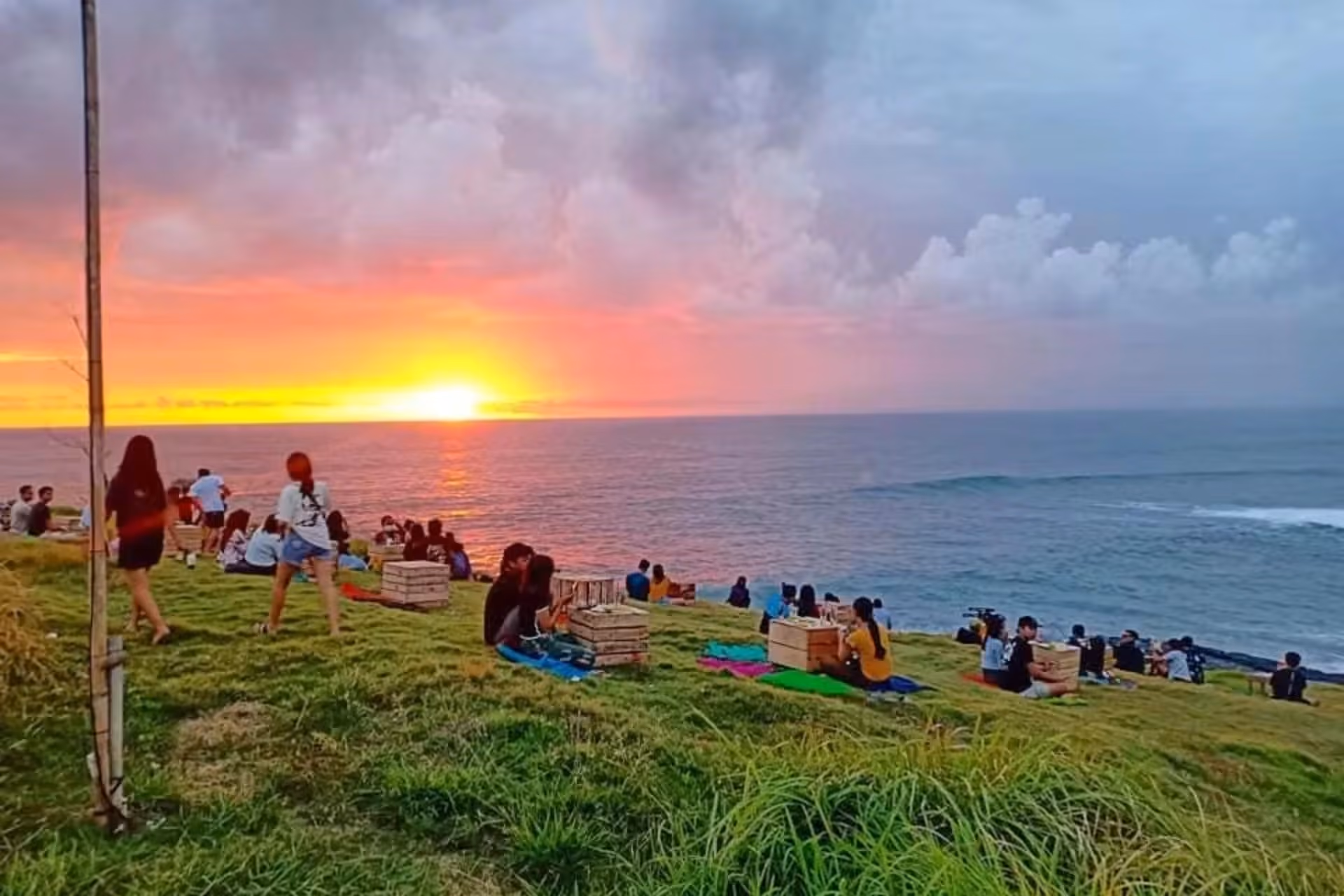 People sitting on grass watching sunset at Love Beach