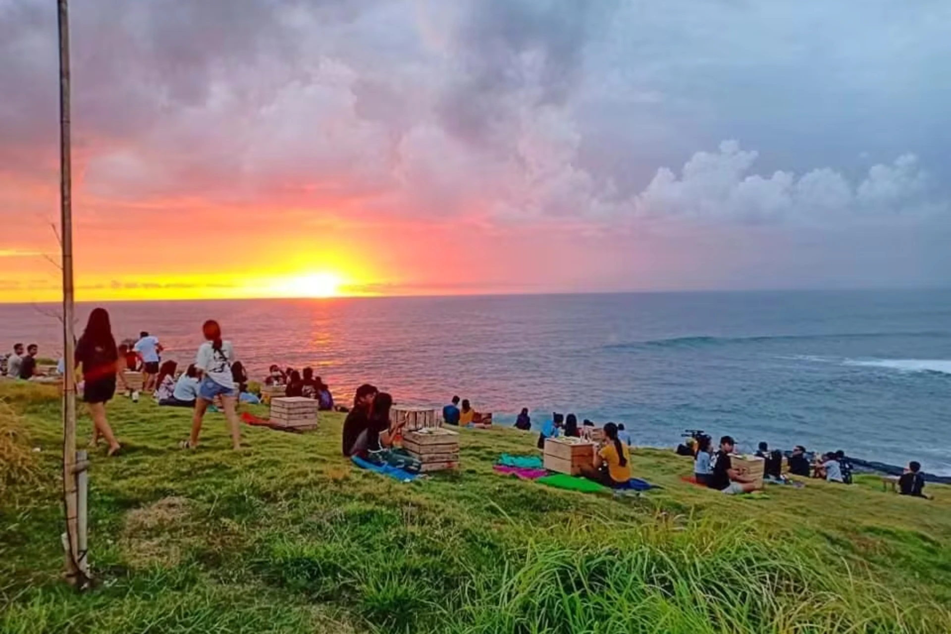 People sitting on grass watching sunset at Love Beach