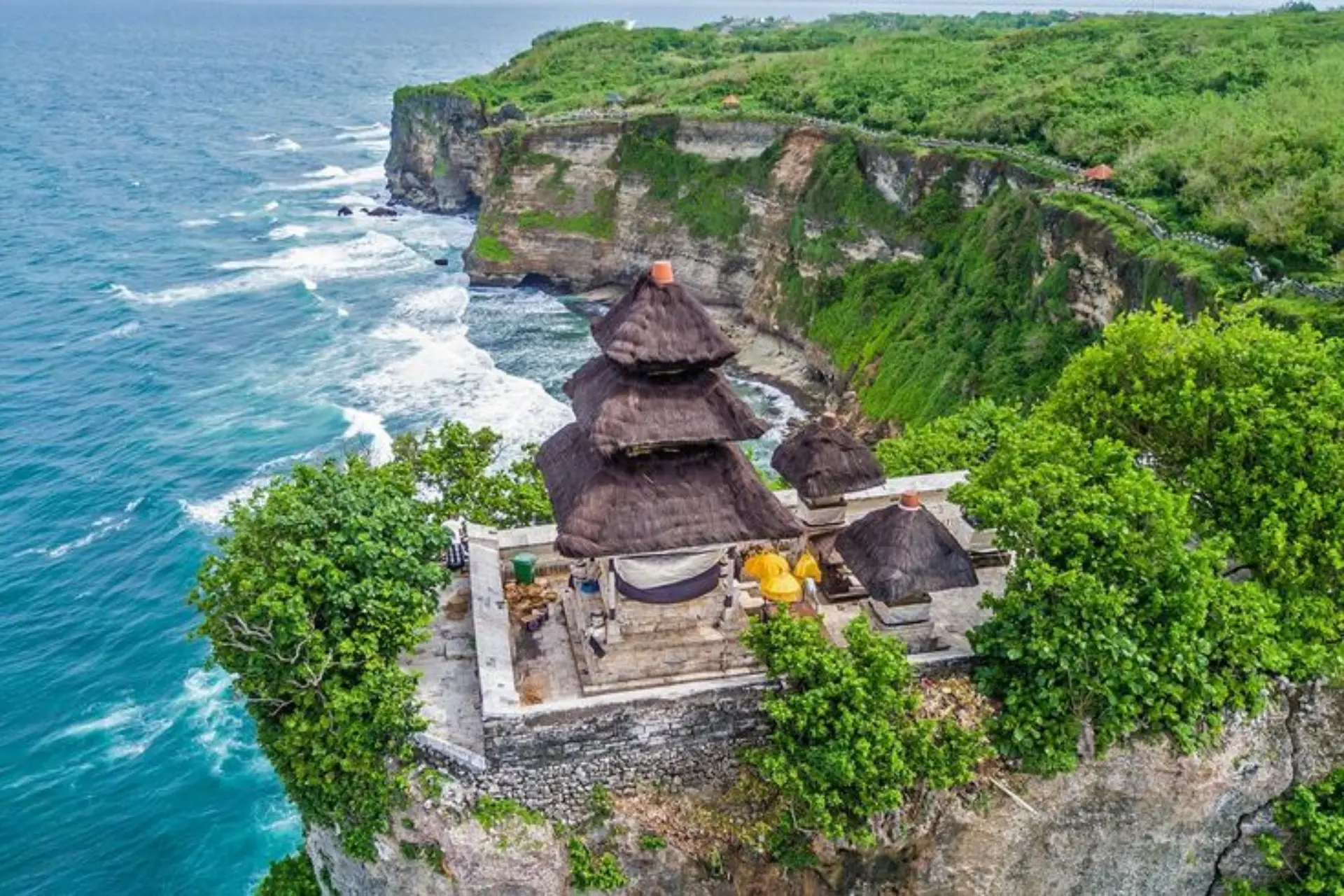 Bali temple with thatched roofs on ocean cliff