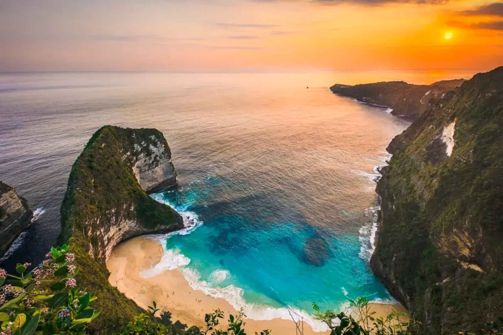 Kelingking Beach with tall cliffs and turquoise water at sunset