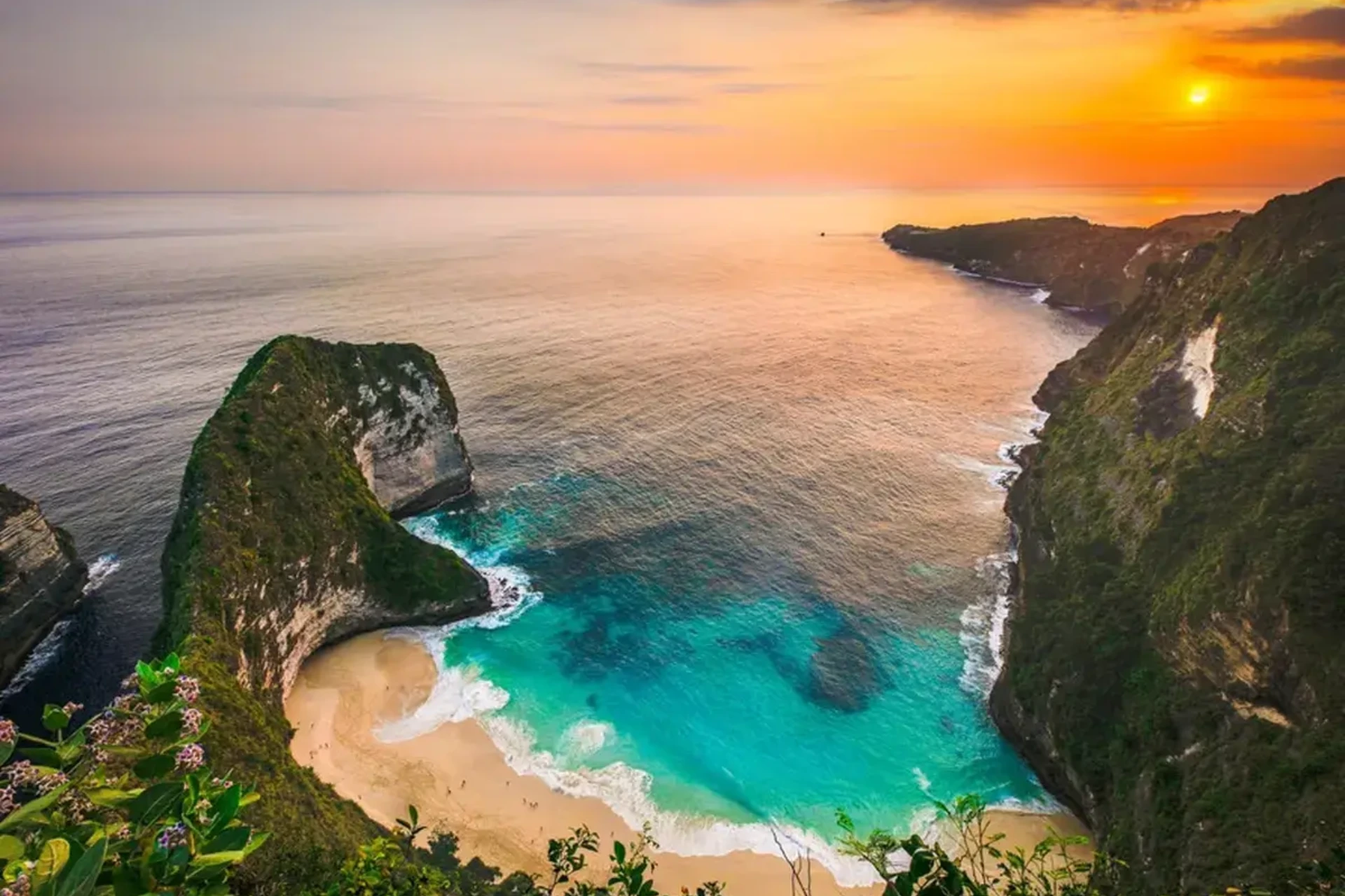 Kelingking Beach with tall cliffs and turquoise water at sunset