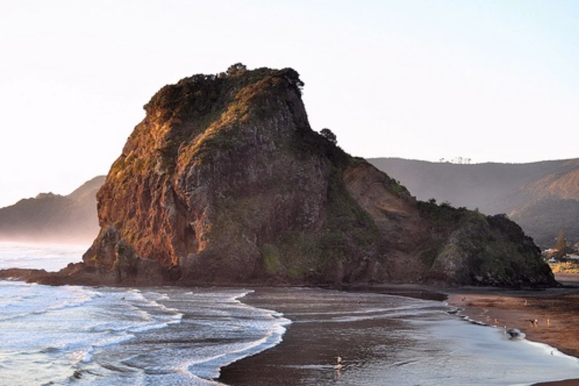 Lion Rock beach with dark sand and waves, New Zealand
