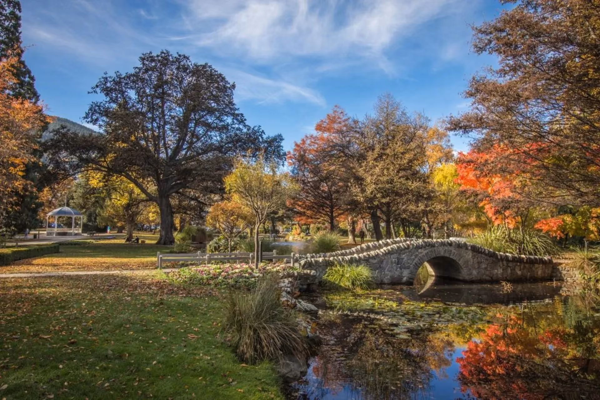Stone bridge over stream in Queenstown autumn garden park