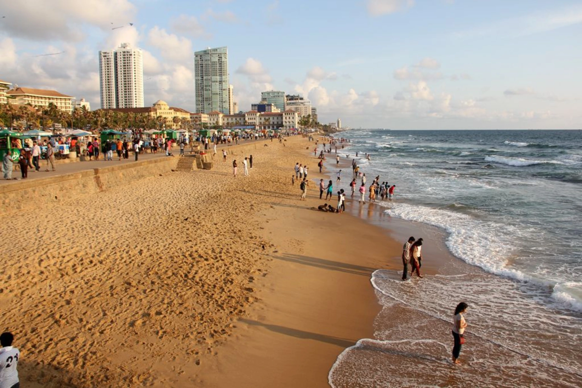 Crowded beach with swimmers and buildings in Colombo, Sri Lanka