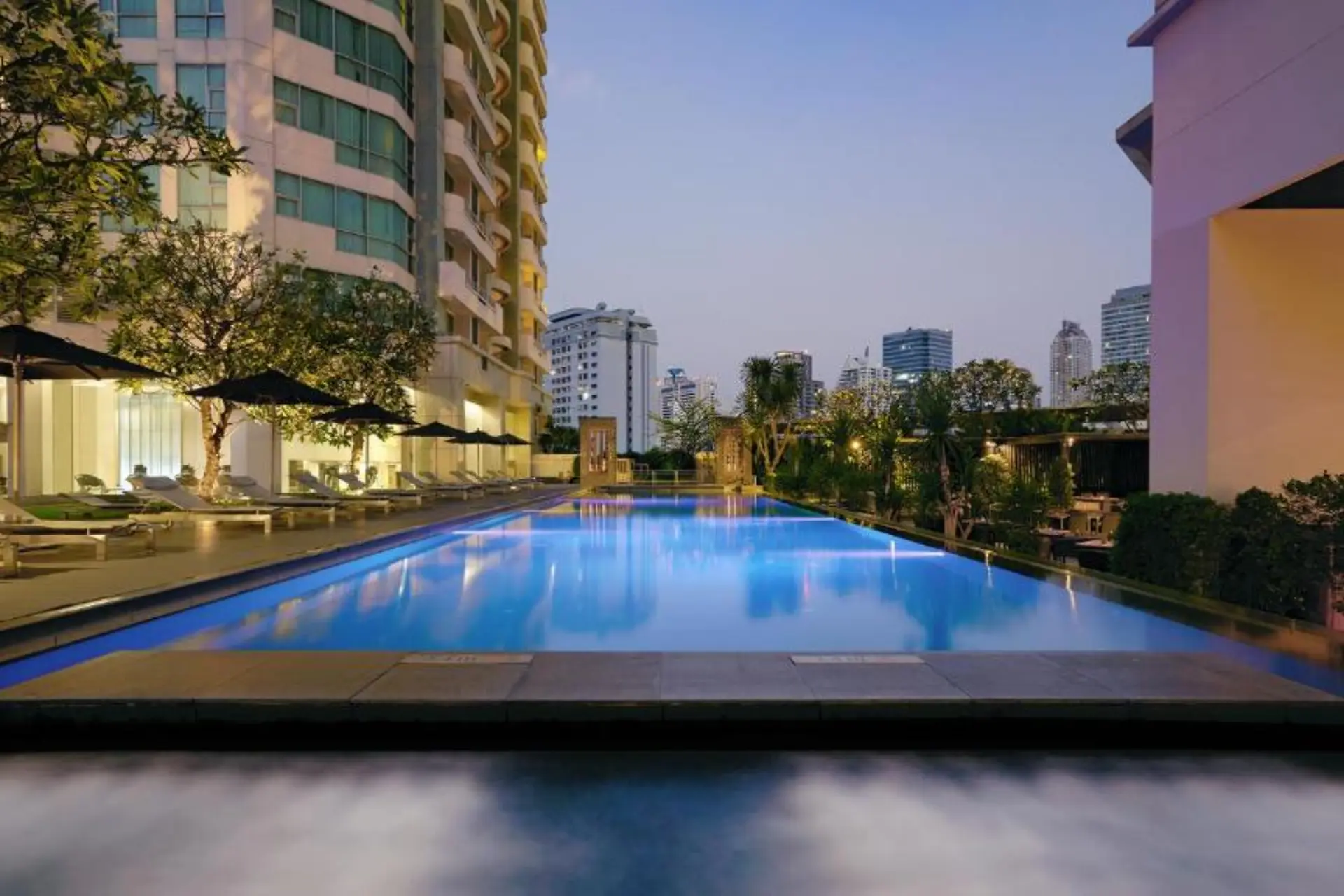 JC Kevin rooftop pool with city buildings at dusk