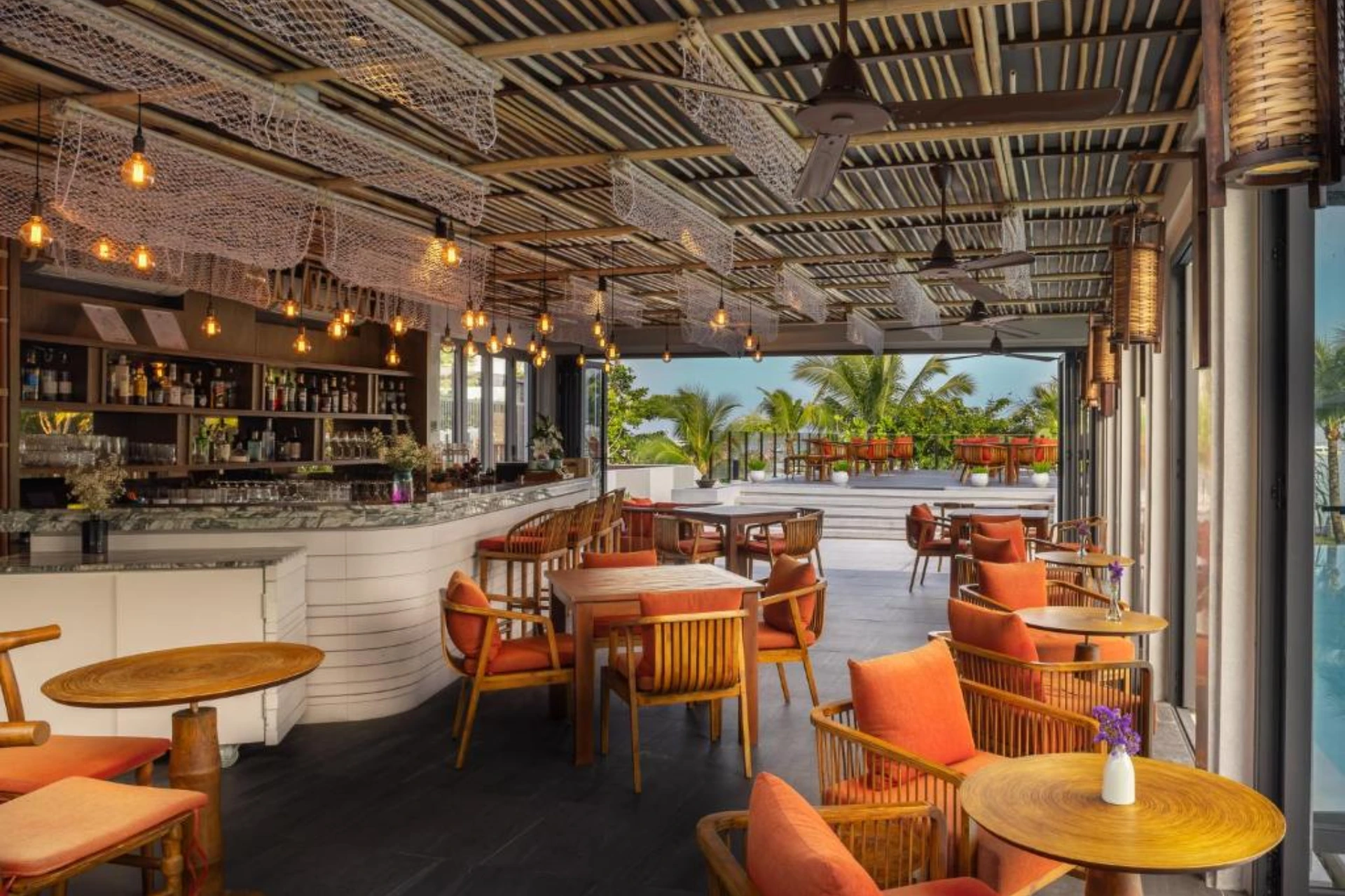 Modern restaurant at The Culture Samui with orange chairs and palm trees