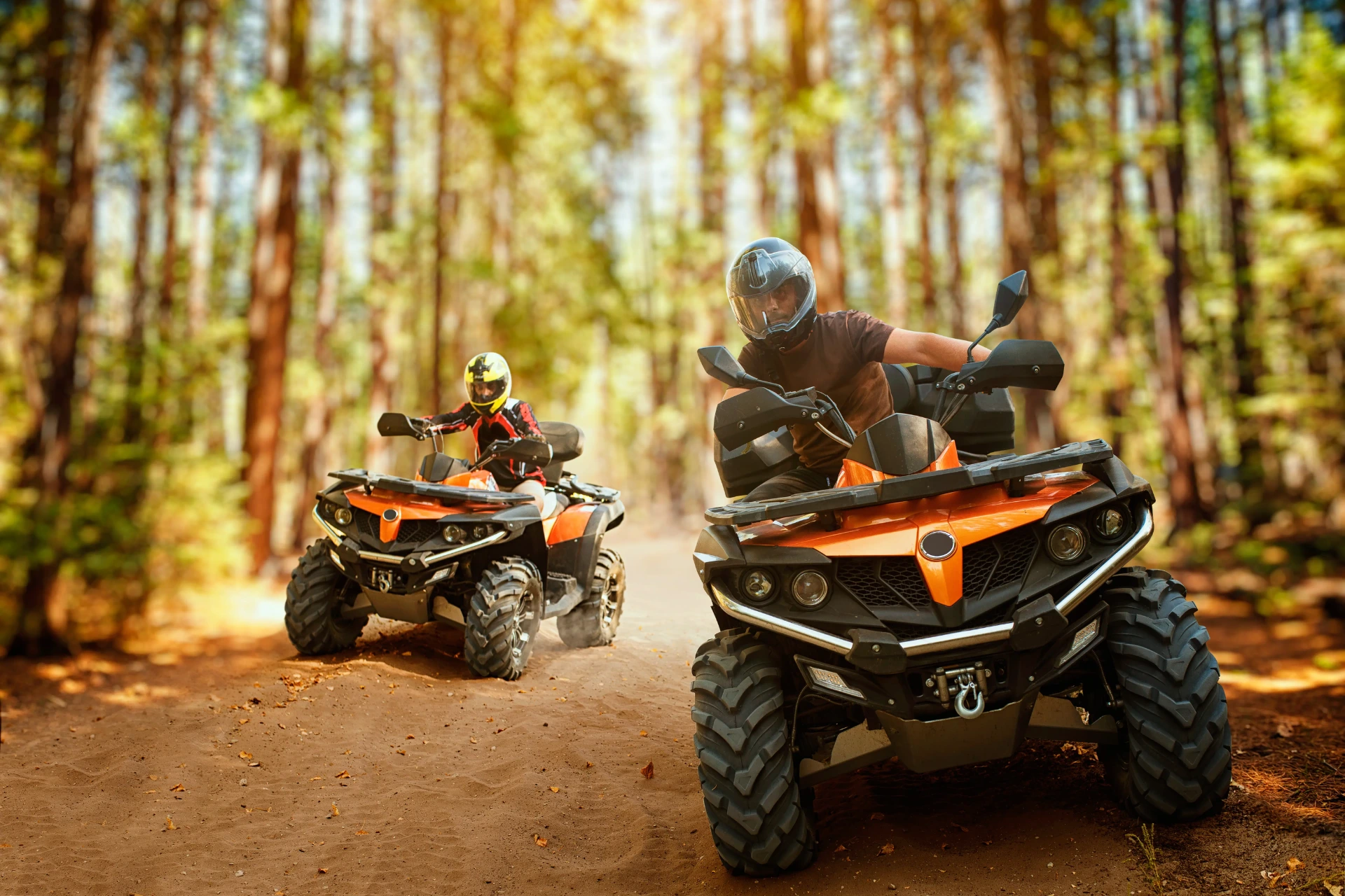 Two riders on orange ATVs on forest path at Khlong Nam