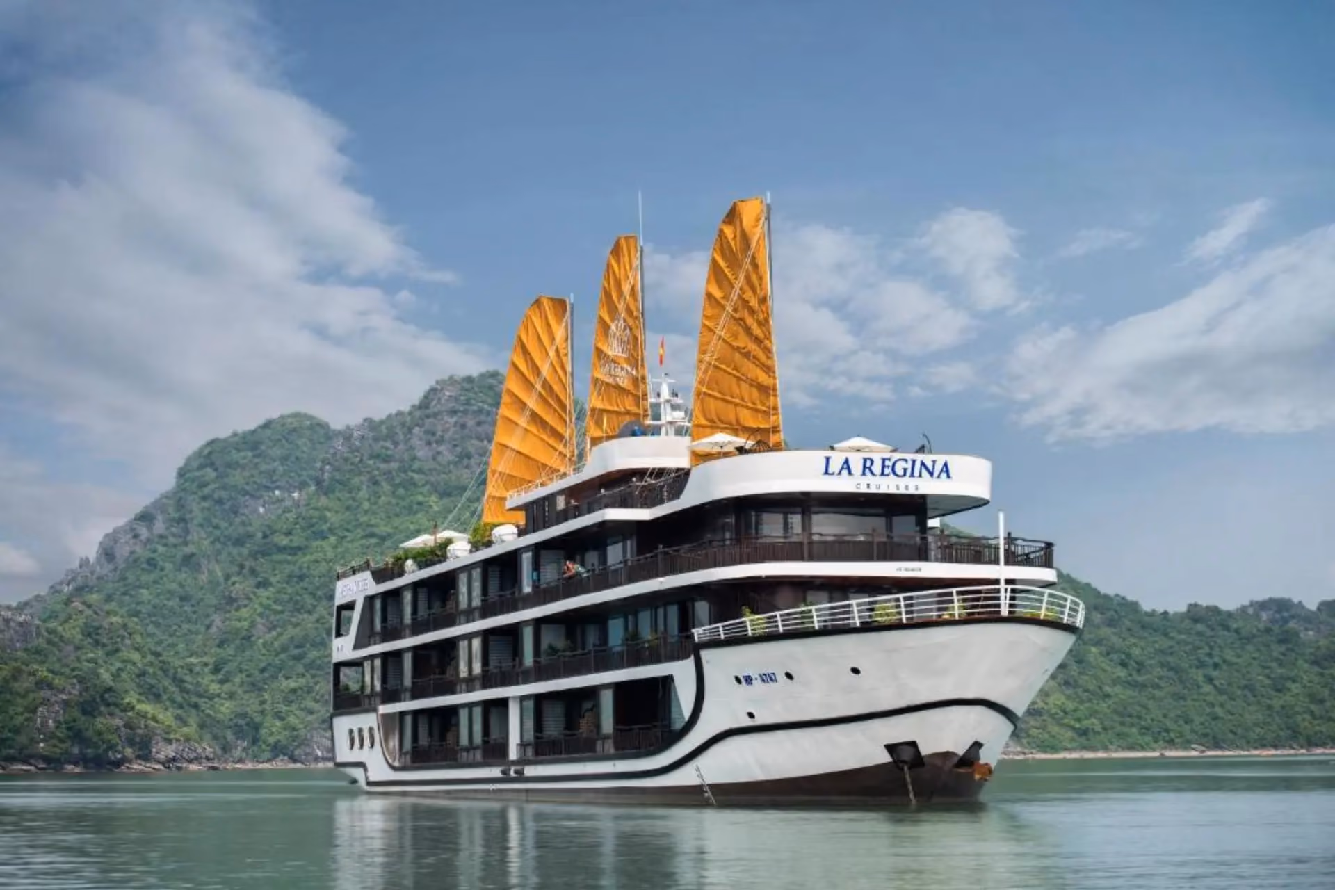 La Regina cruise ship with golden sails on green water