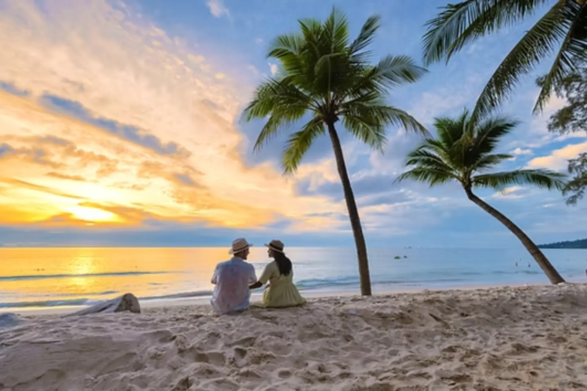 Couple sitting on Phuket beach at sunset