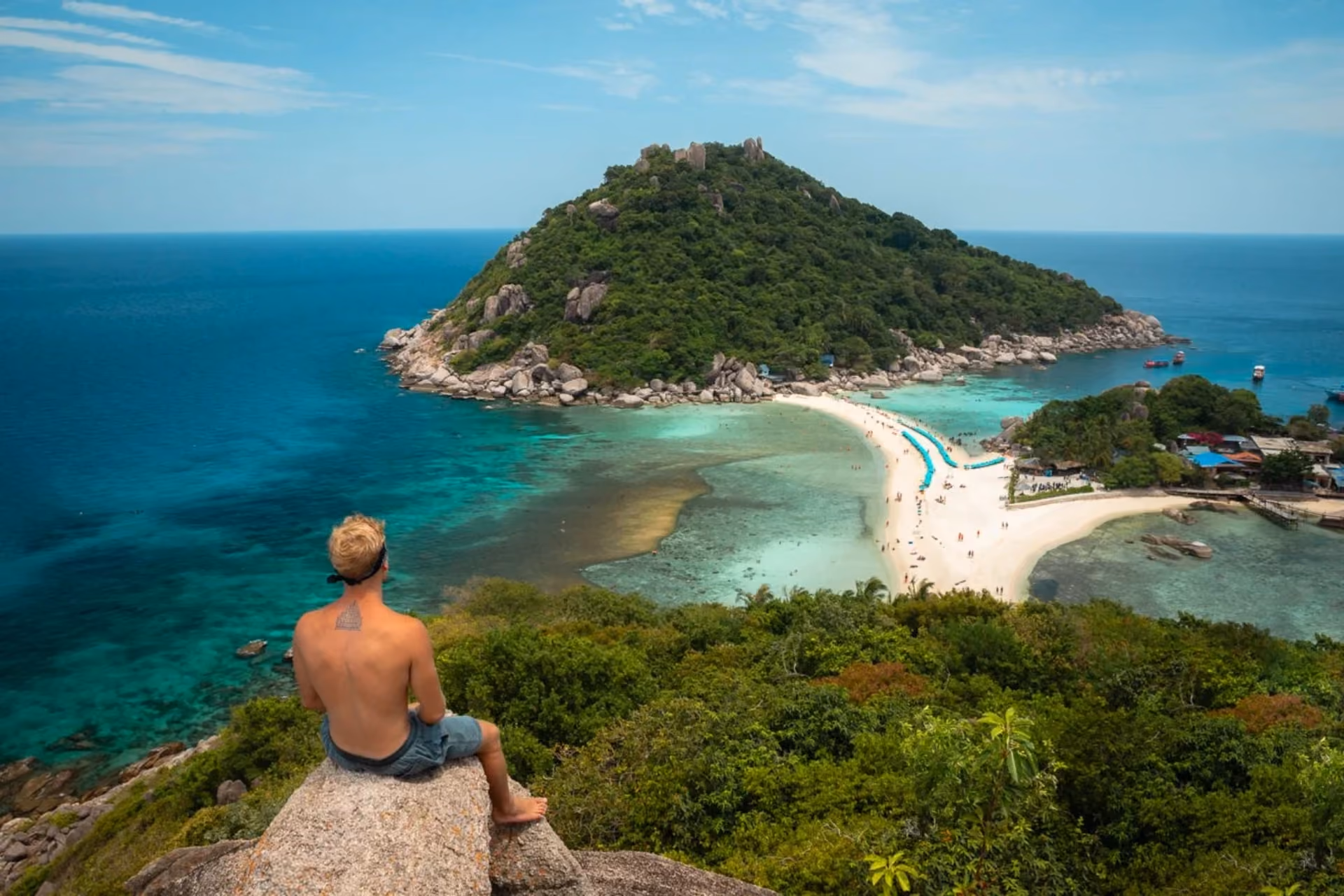 Man sitting on rock overlooking Nang Yuan beach and islands
