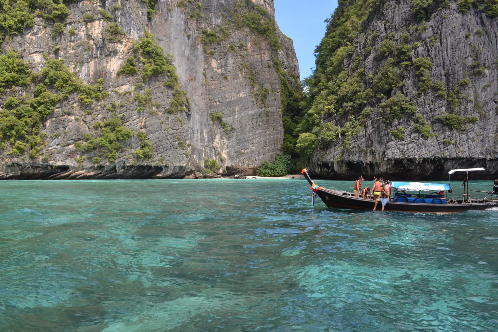 Longtail boat in clear water at Koh Phi Phi cliffs
