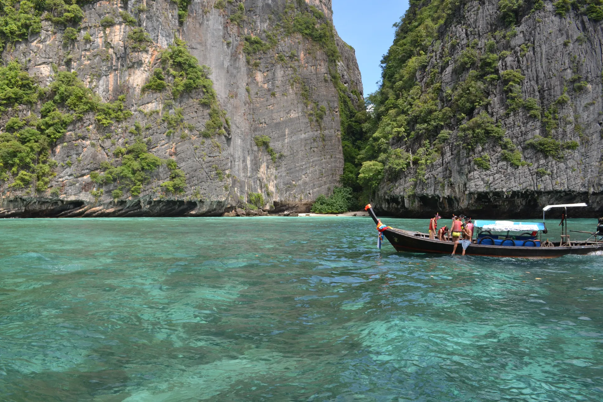 Longtail boat in clear water at Koh Phi Phi cliffs
