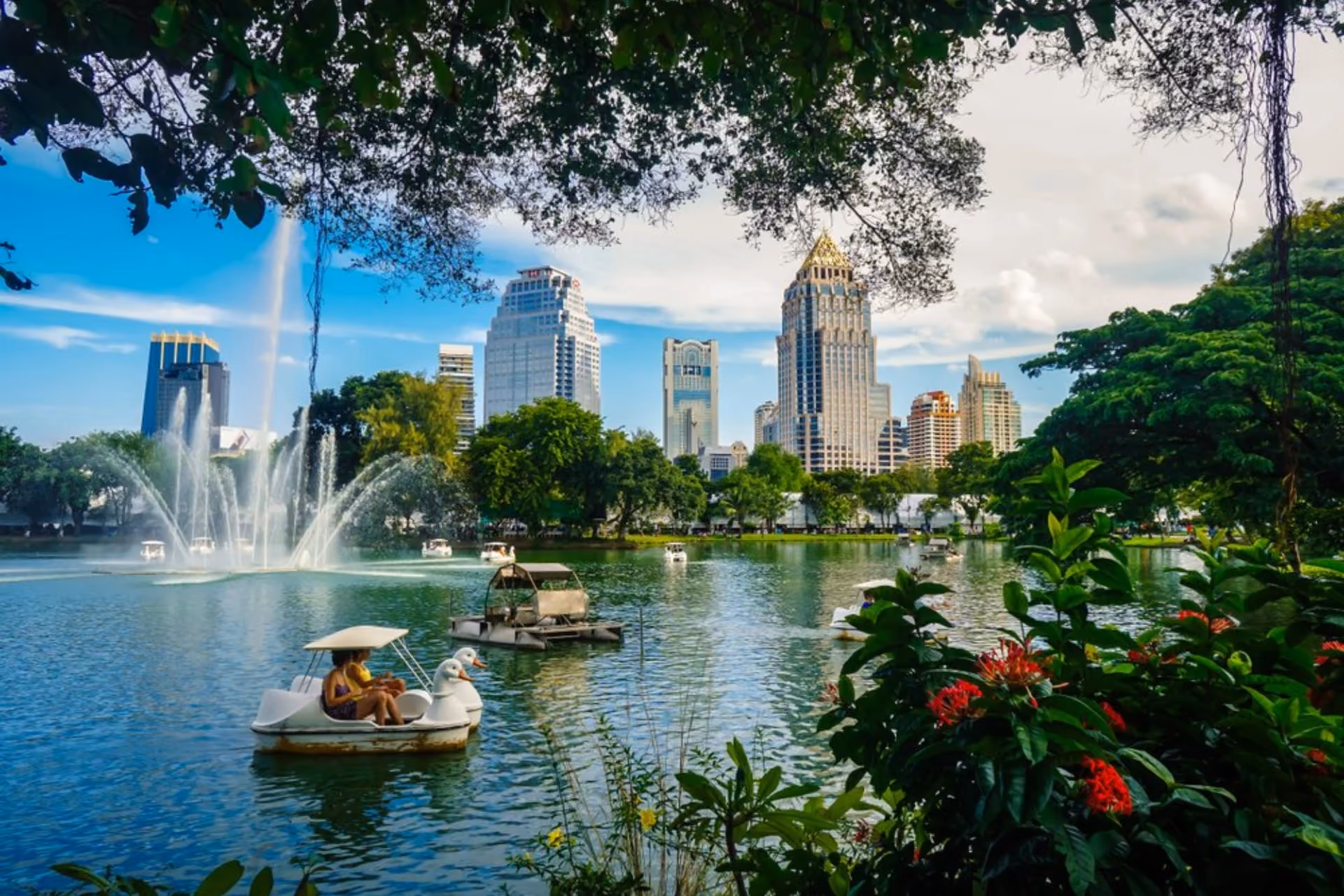Lumpini Park lake with fountains and Bangkok skyscrapers