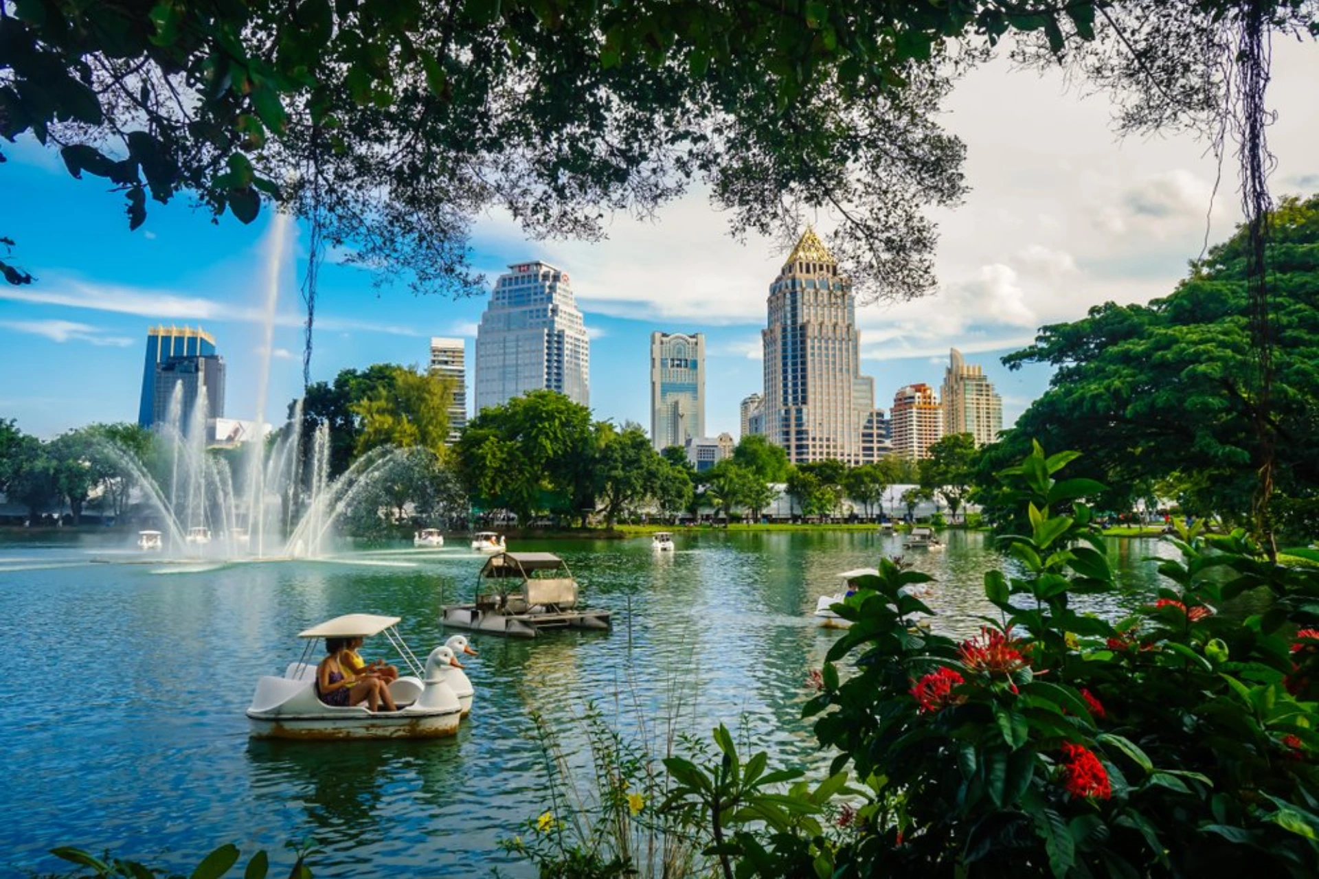 Lumpini Park lake with fountains and Bangkok skyscrapers
