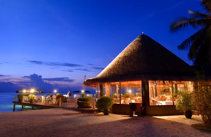 Beach restaurant with thatched roof at dusk