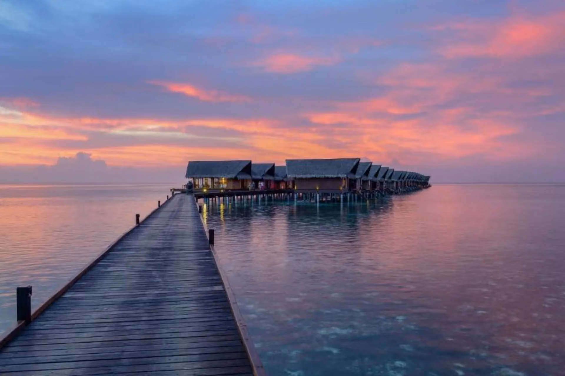 Adaaran Select wooden pier with overwater bungalows at sunset