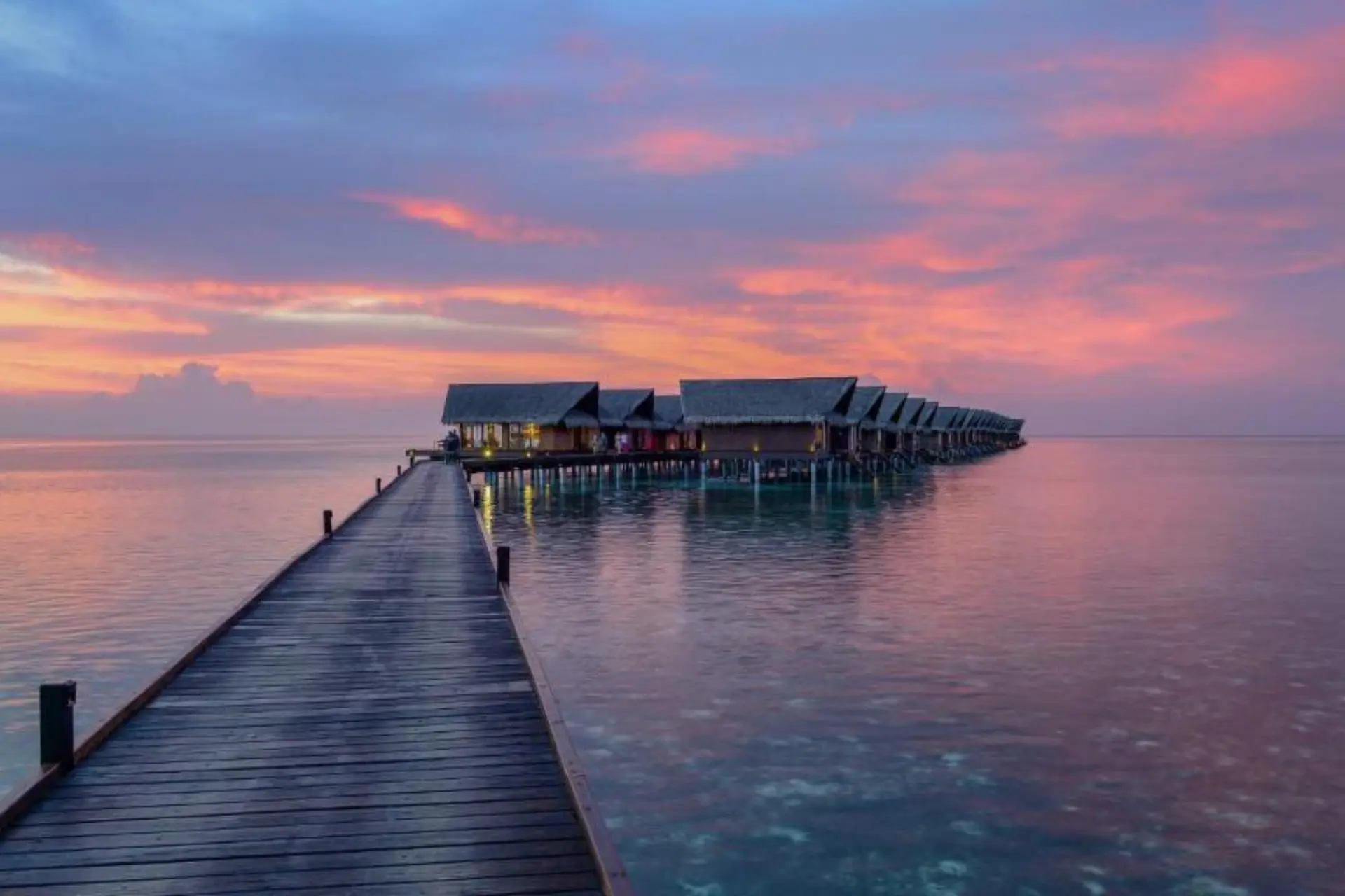 Adaaran Select wooden pier with overwater bungalows at sunset