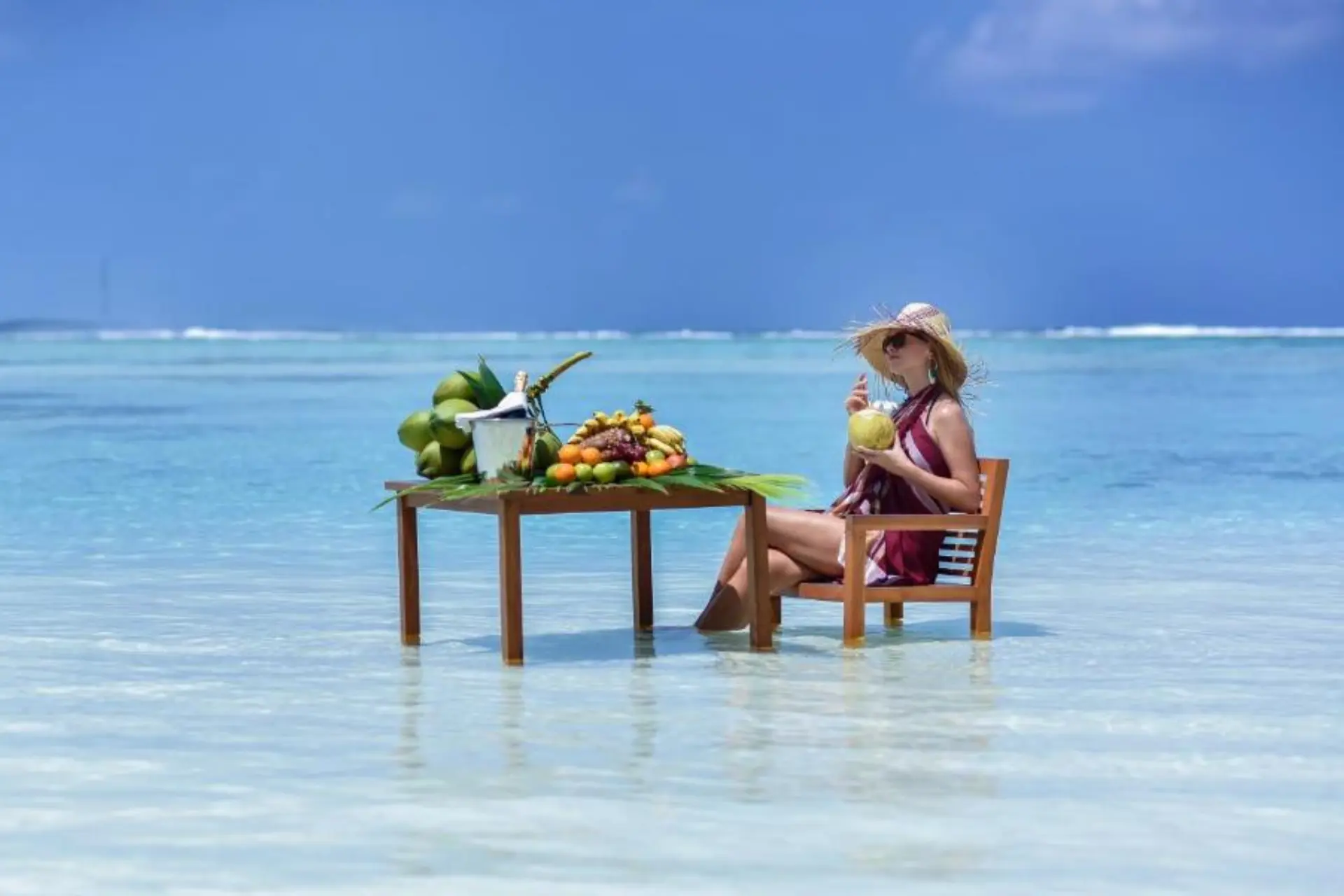 Woman sitting in shallow water at Adaaran Select with fruit table