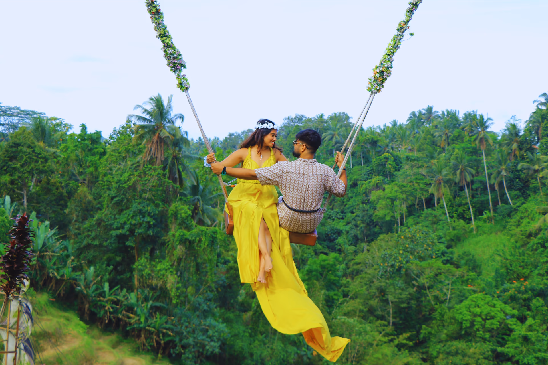Couple on rope swing over Bali jungle trees