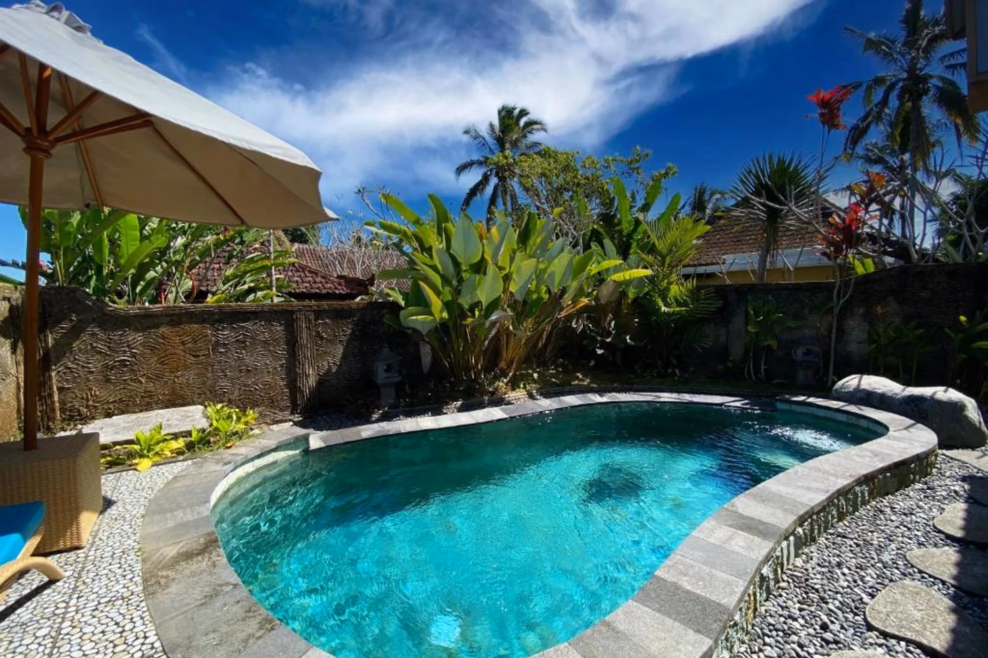 Sebatu By Villas Resort pool with palm trees and blue sky
