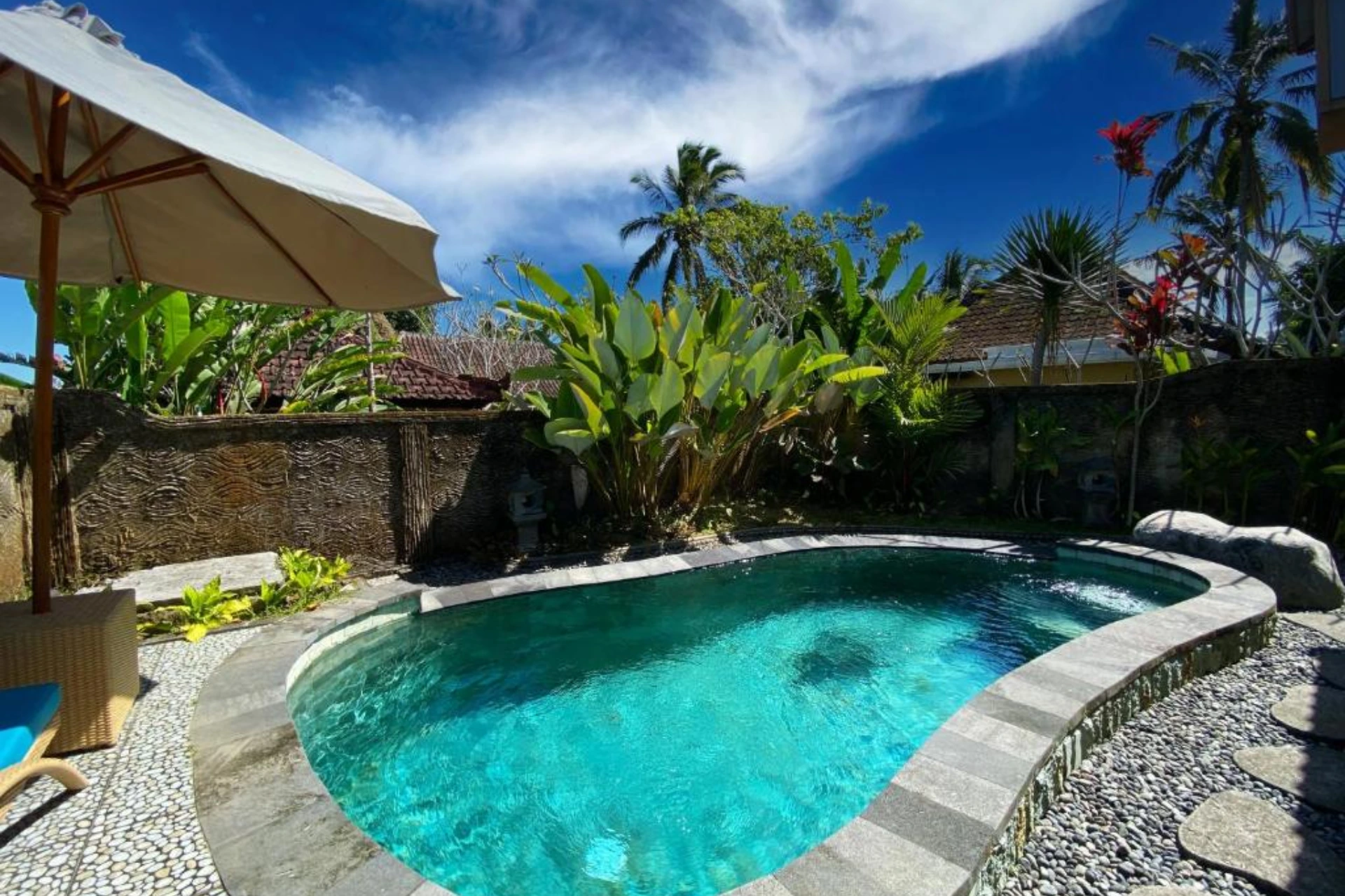 Sebatu By Villas Resort pool with palm trees and blue sky