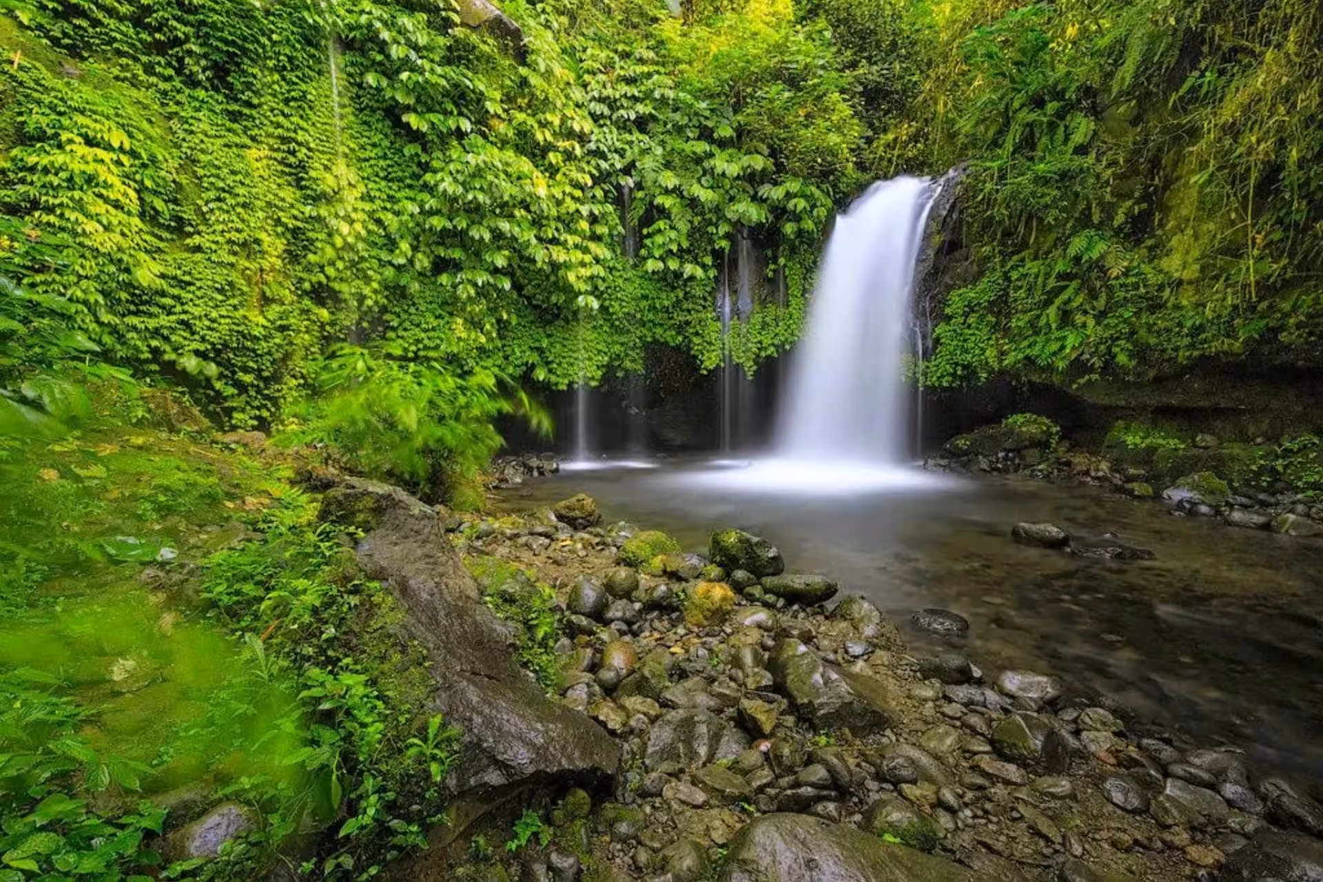 Yeh Ho Waterfall cascading into pool surrounded by green plants