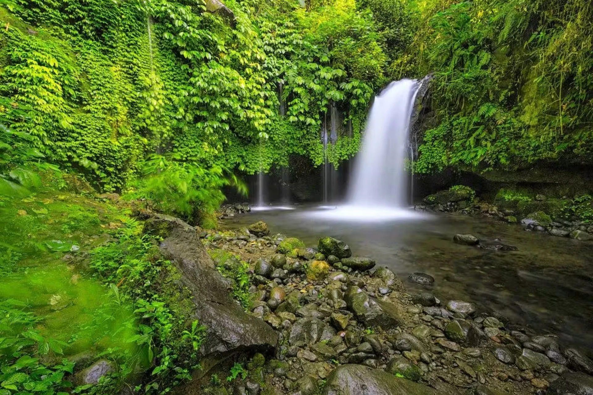 Yeh Ho Waterfall cascading into pool surrounded by green plants
