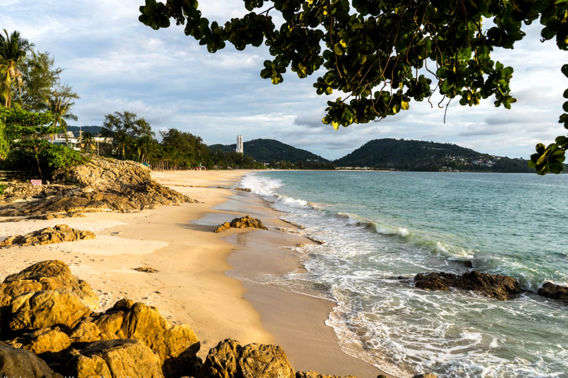 Sandy beach with rocks and waves at Patong Beach