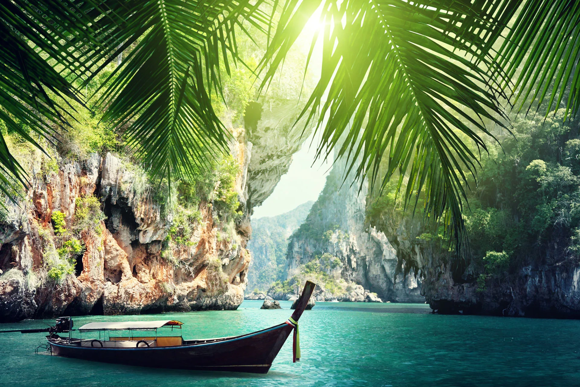 Wooden boat on blue-green water between tall cliffs