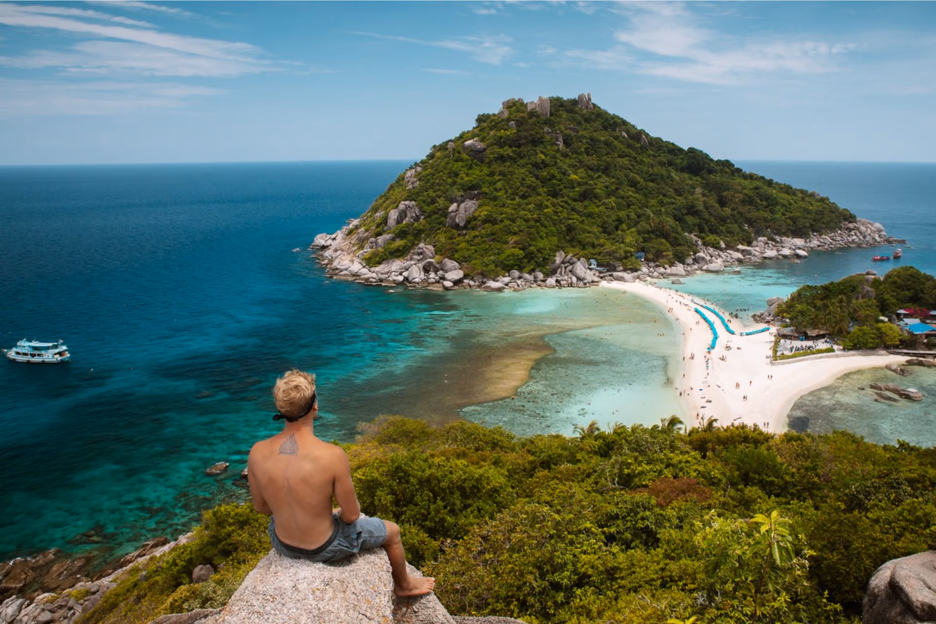 Man sitting on rock overlooking Thai island beach