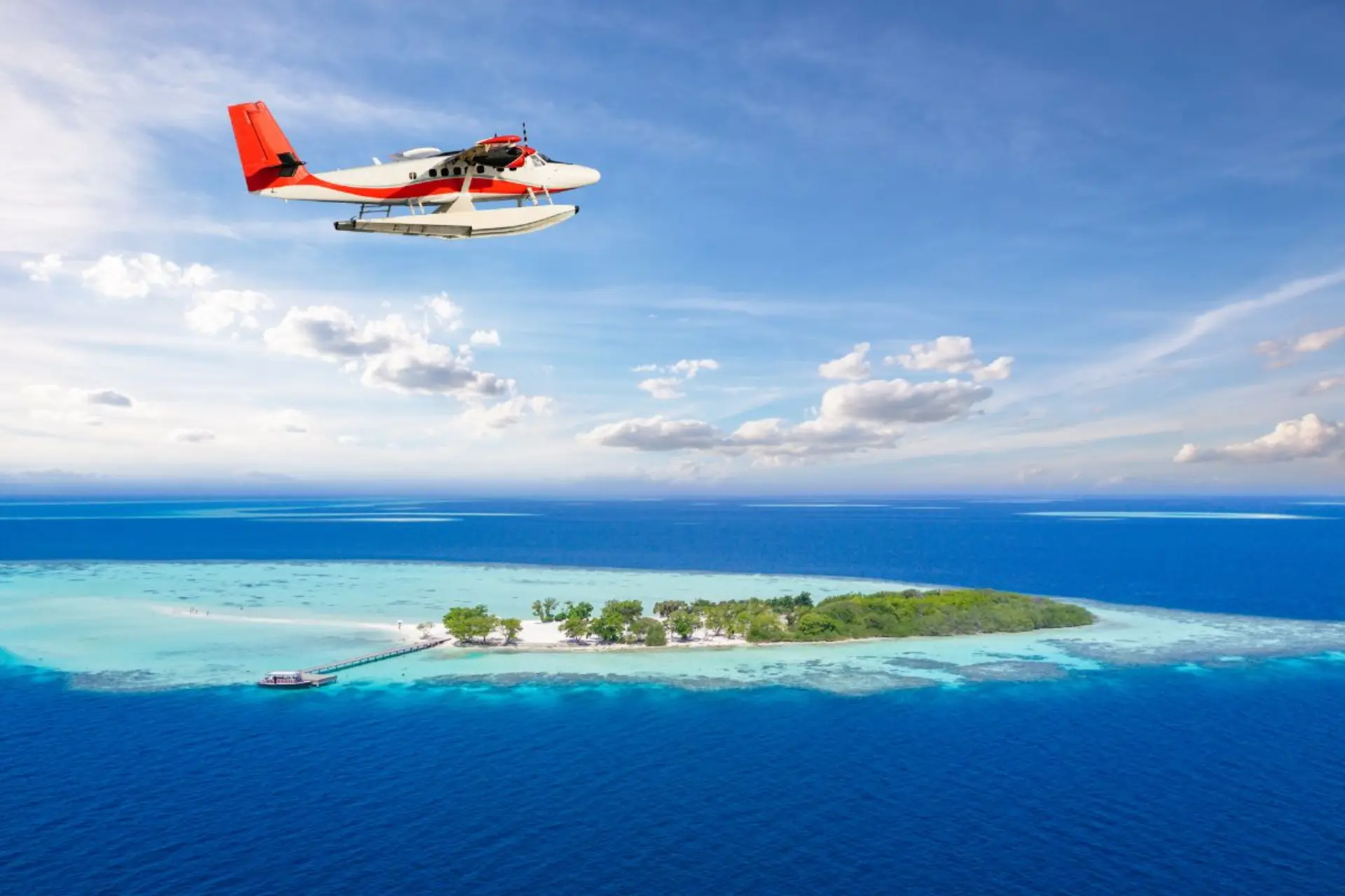 Seaplane flying over Kanifushi island with blue water below