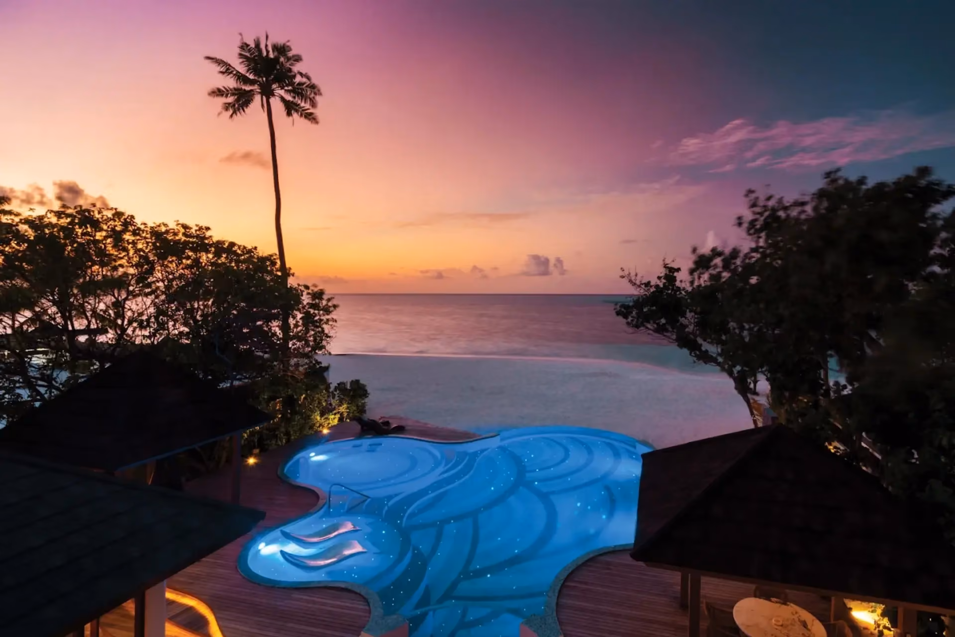 Glowing pool at Atmosphere Kanifushi Resort at sunset