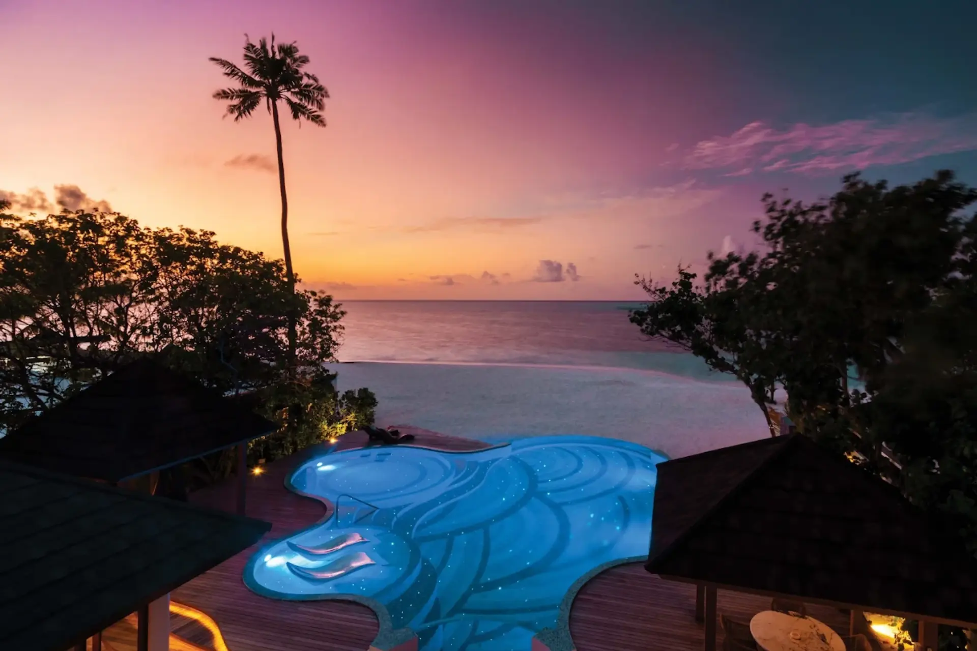 Glowing pool at Atmosphere Kanifushi Resort at sunset