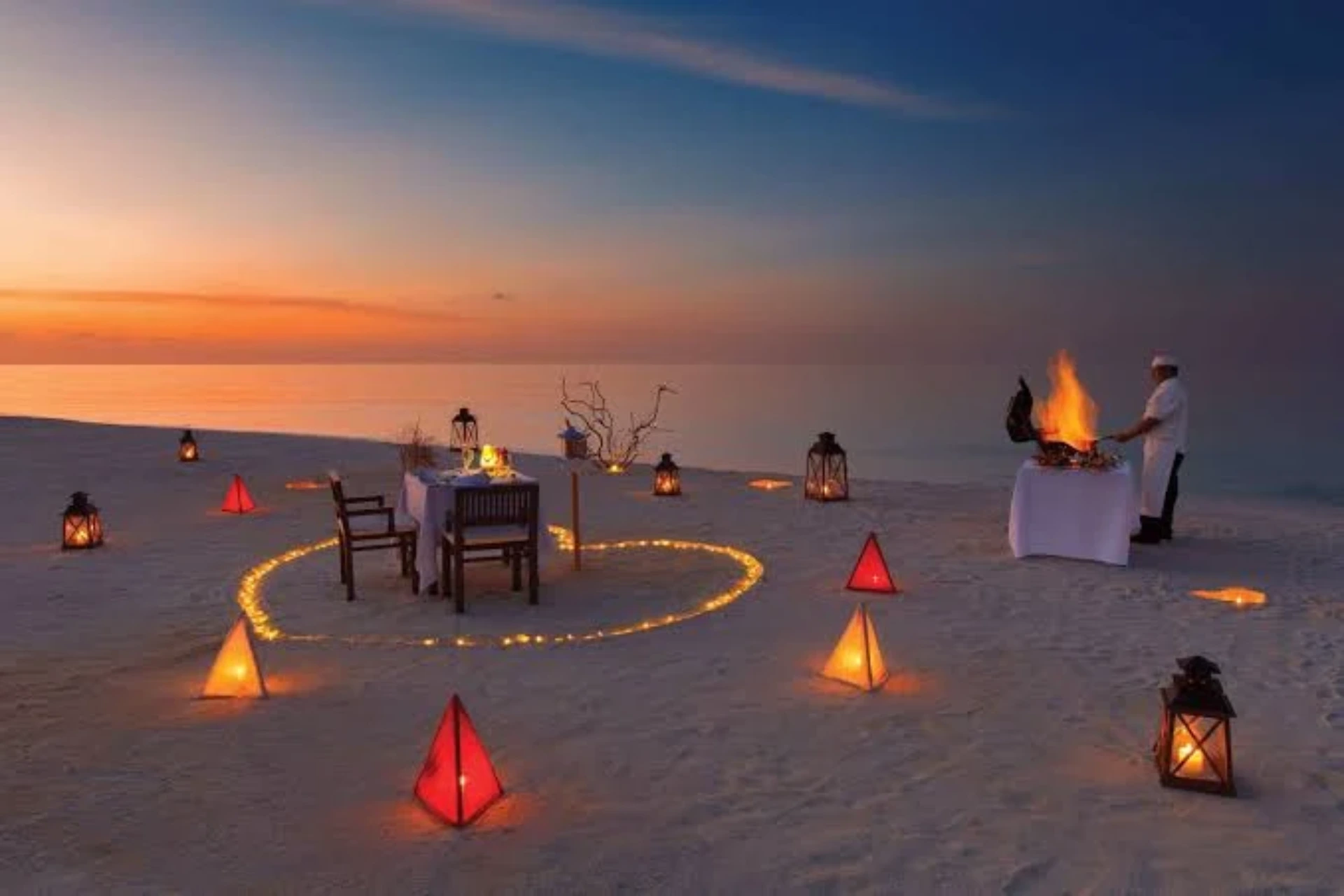 Romantic beach dinner setup at Kanifushi at sunset