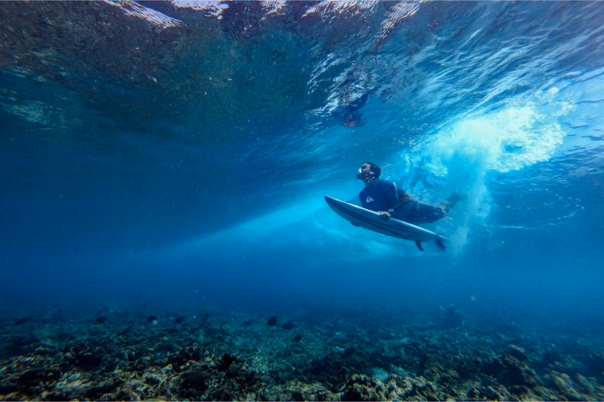 Surfer paddling out on clear blue ocean water