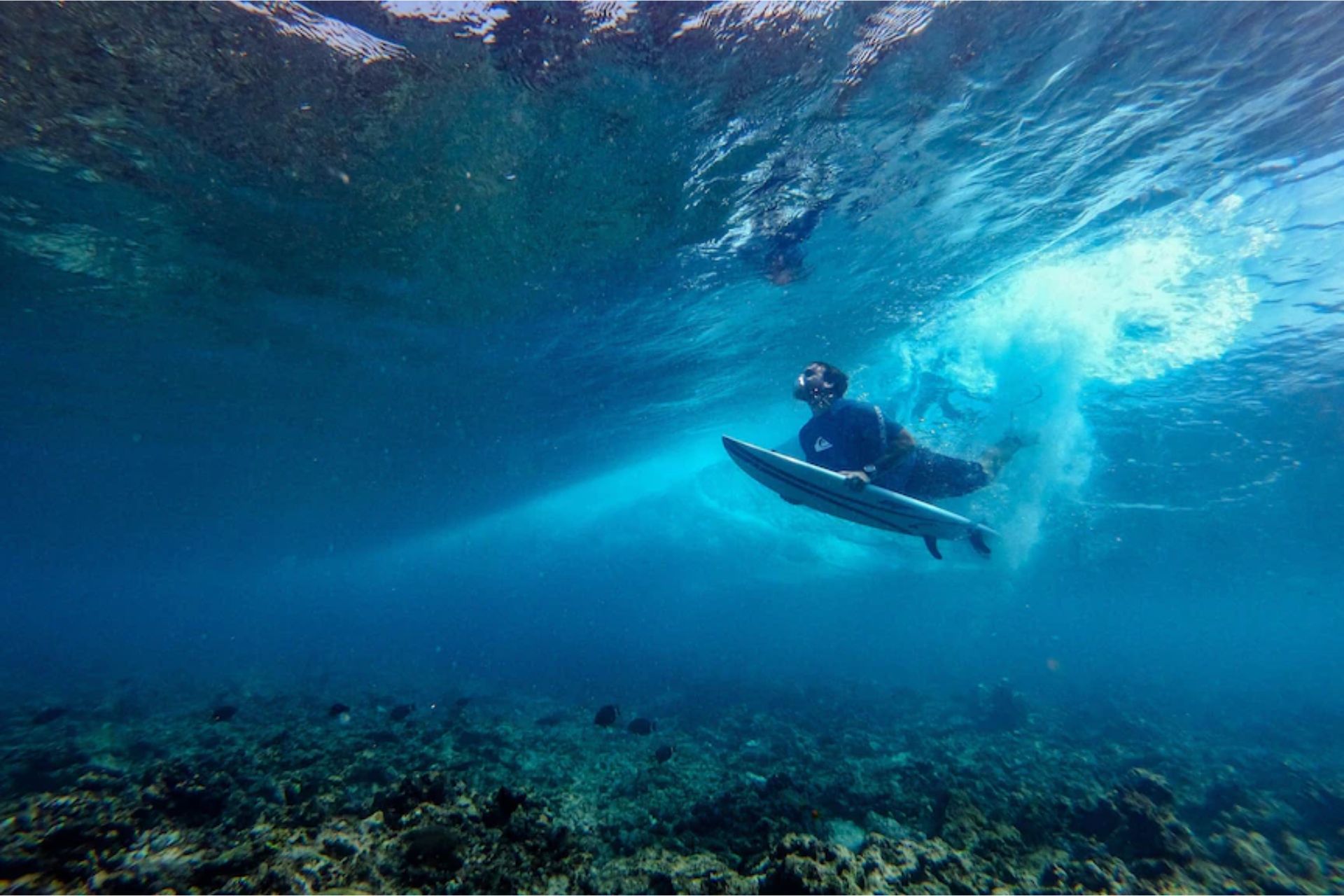 Surfer paddling out on clear blue ocean water