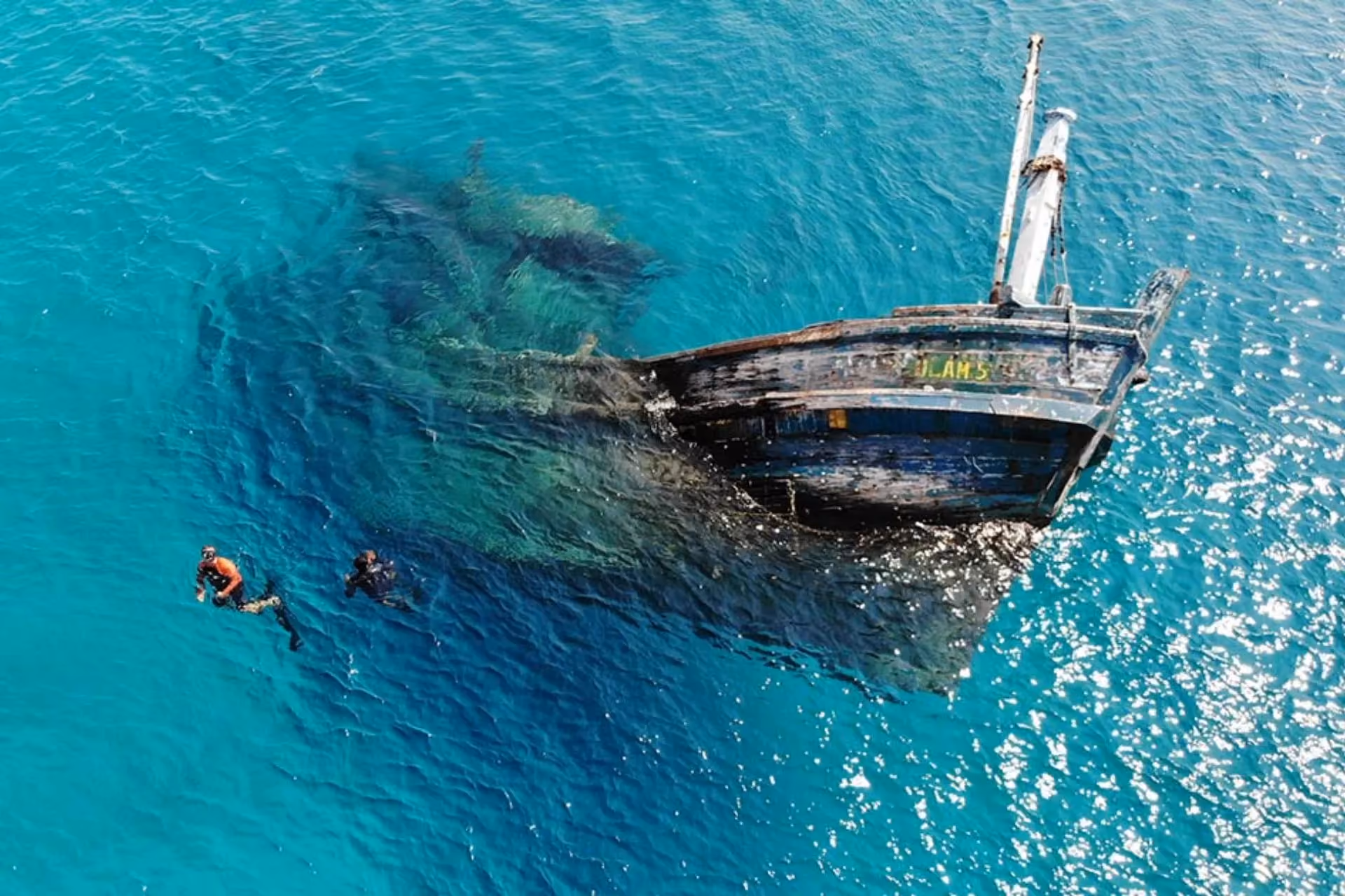 Swimmers next to sunken ship in clear water