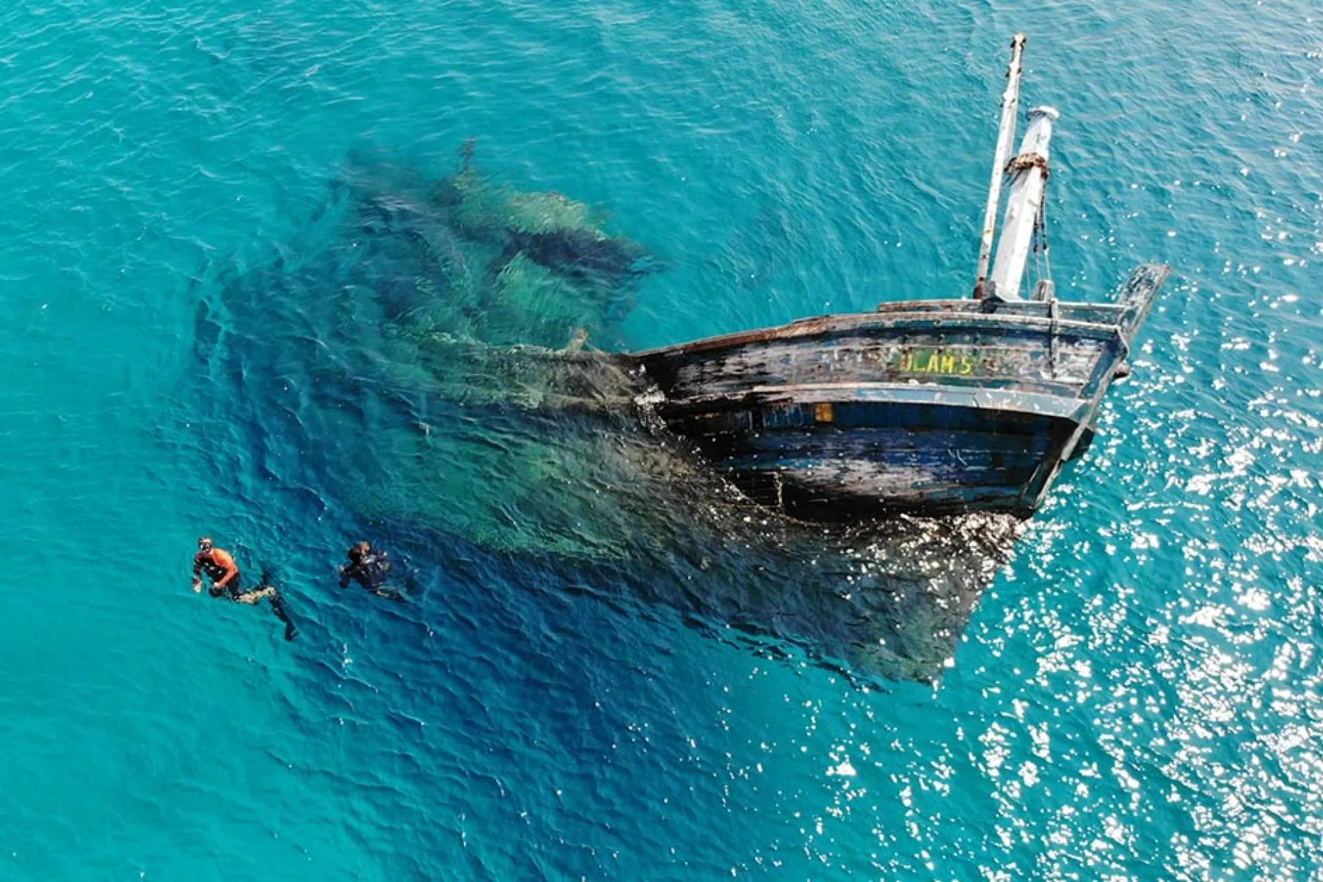 Swimmers next to sunken ship in clear water