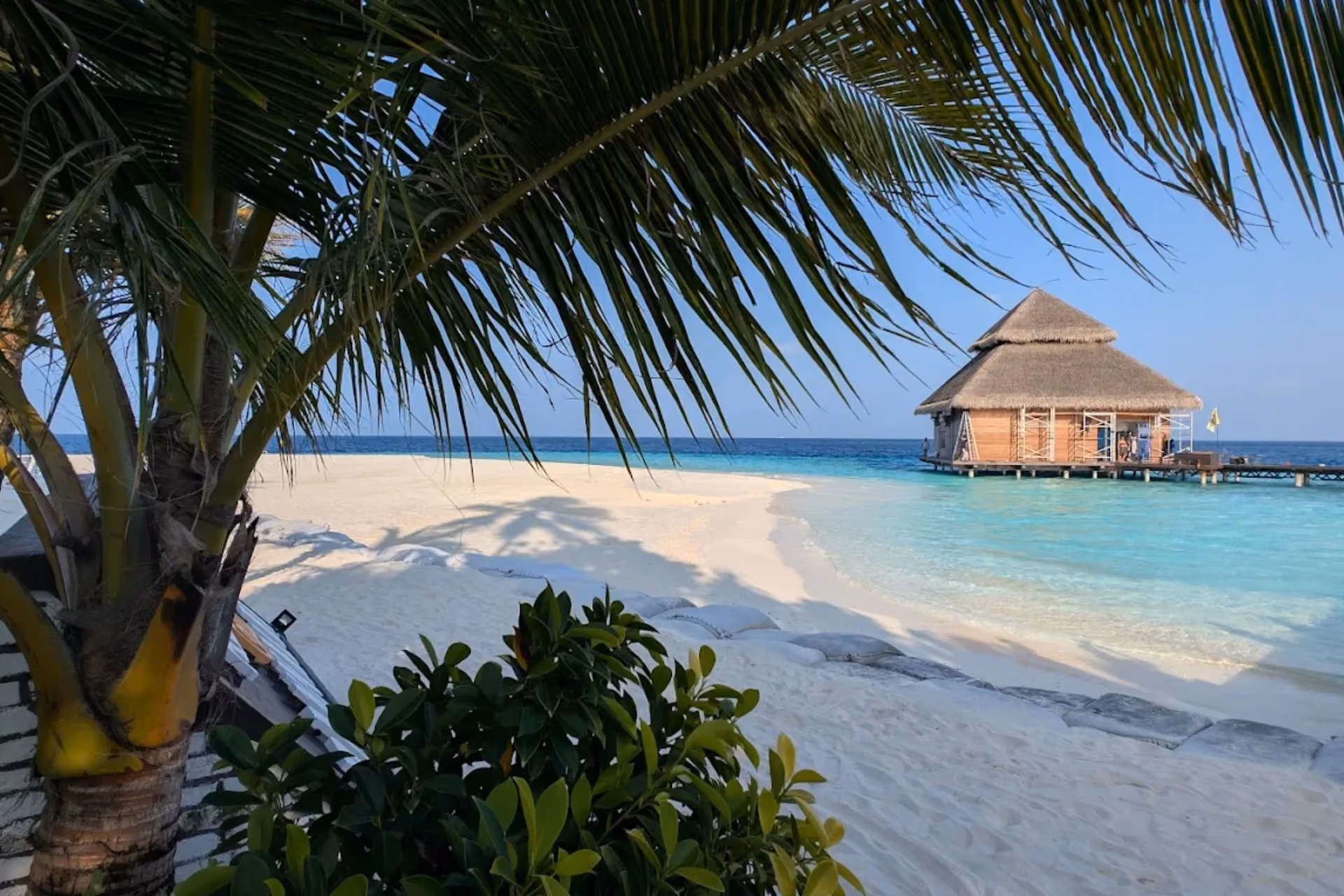 Palm trees frame sandy beach at Adaaran Rannhali with wooden hut