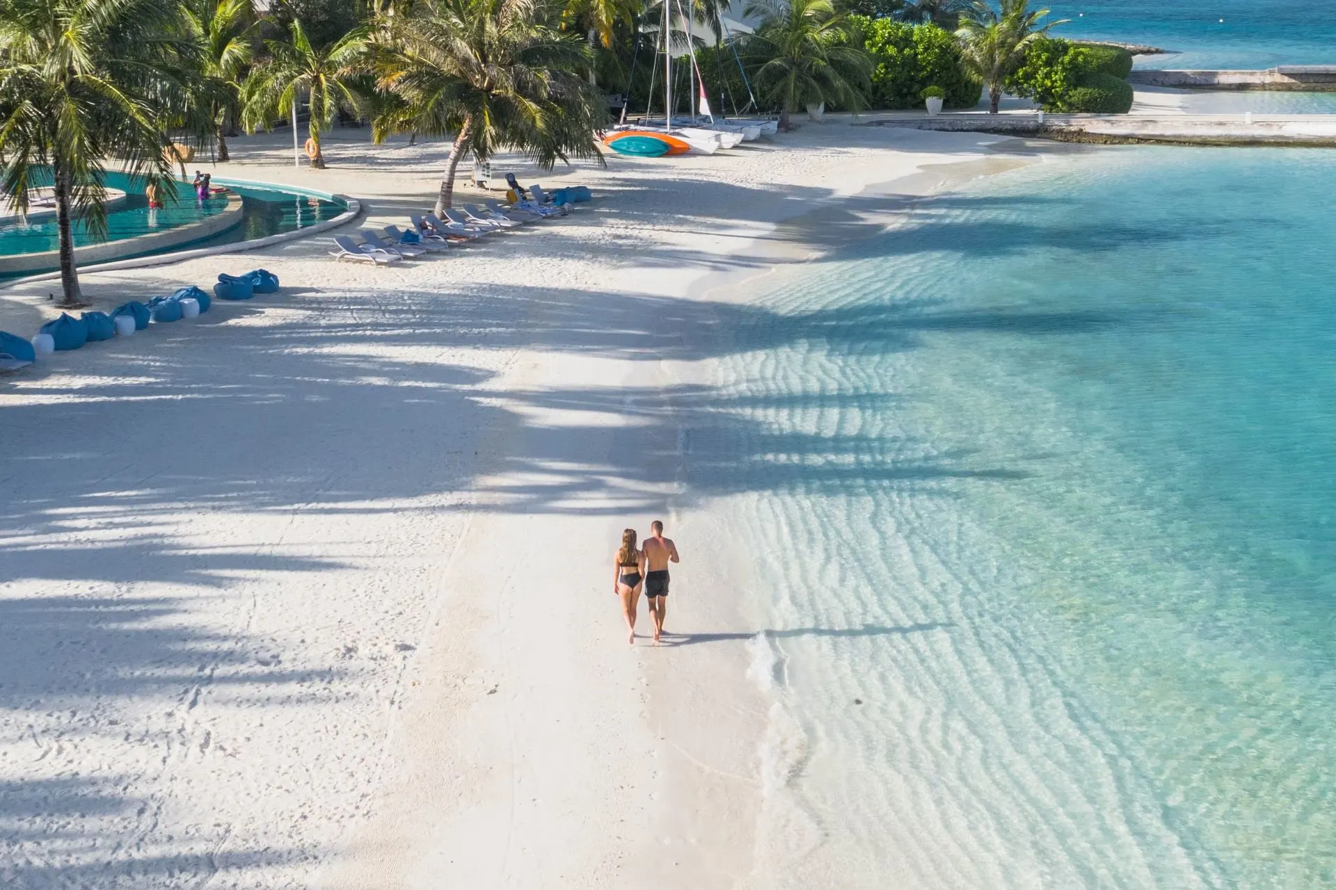 Couple jogging along white sand beach with clear water